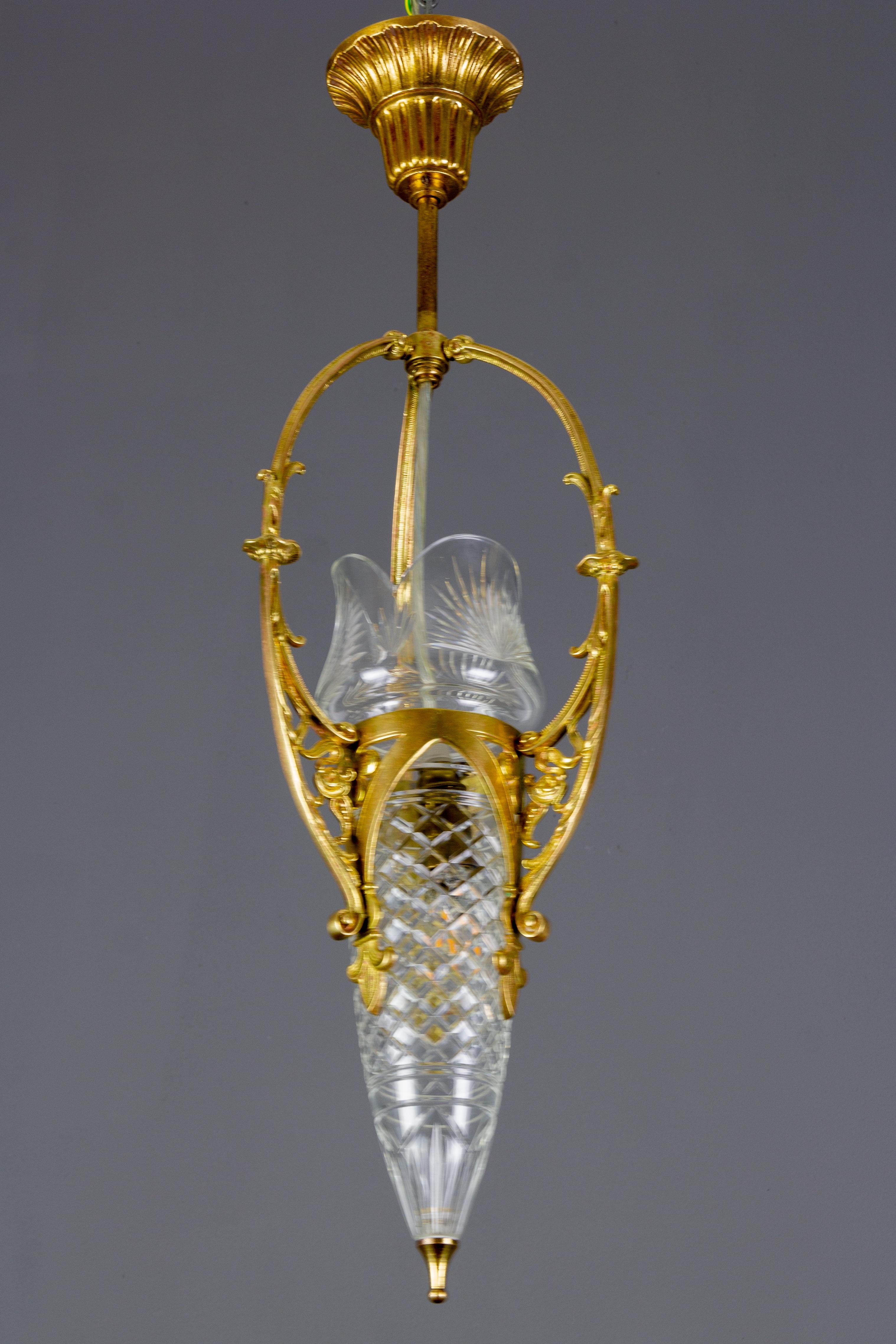 French Art Nouveau pendant light fixture with beautifully shaped brass frame and cut crystal glass lampshade.
One socket for the E14 size light bulb.
Dimensions: Height 65 cm / 25.6 in, diameter 16 cm / 6.3 in.