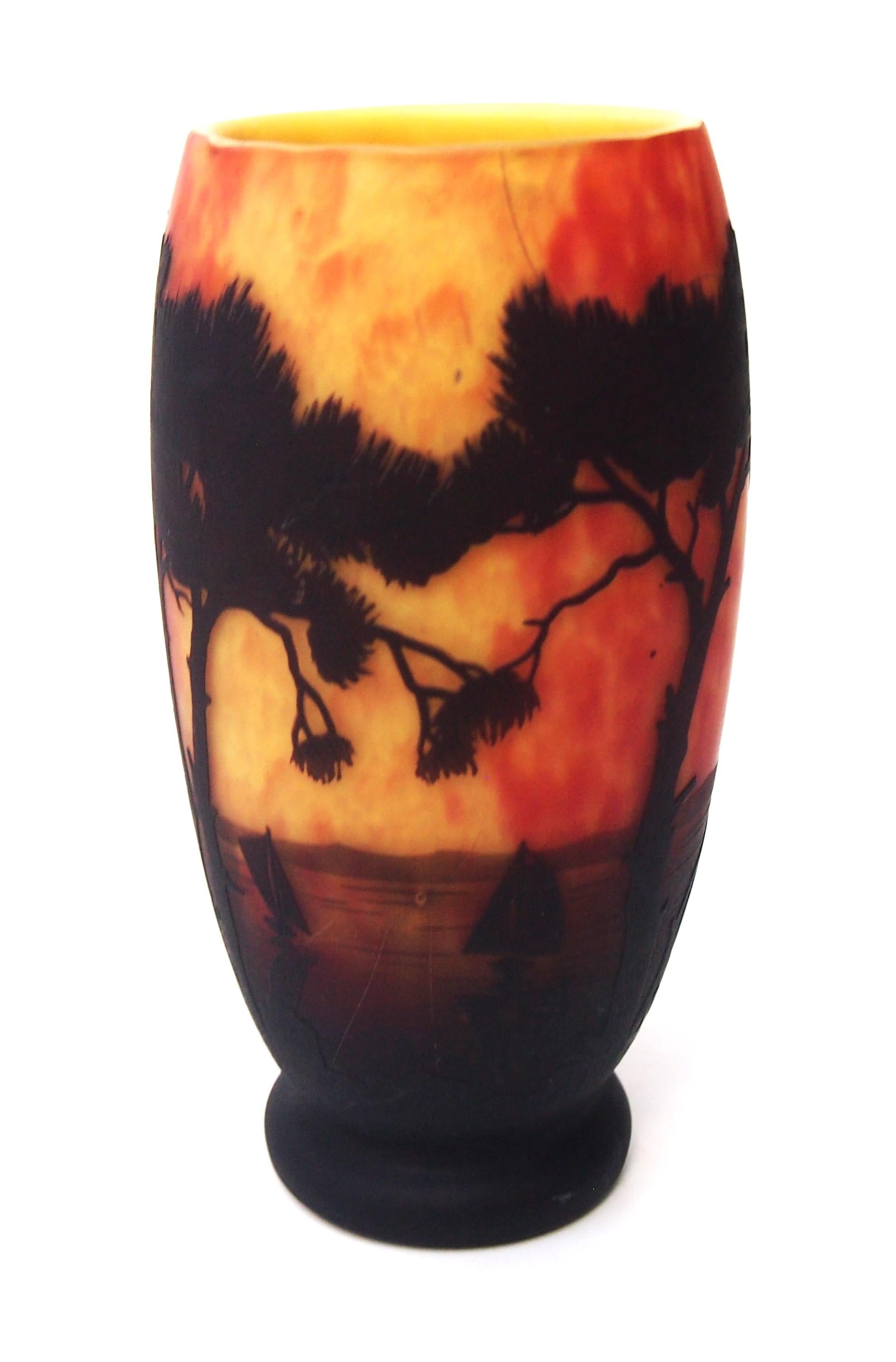 Vase camée classique Art Nouveau Daum de taille moyenne représentant un paysage marin tropical avec des arbres exotiques, la mer et divers voiliers orientaux en noir (brun foncé) sur une couche jaune-rouge tachetée. Une grande partie de la couche