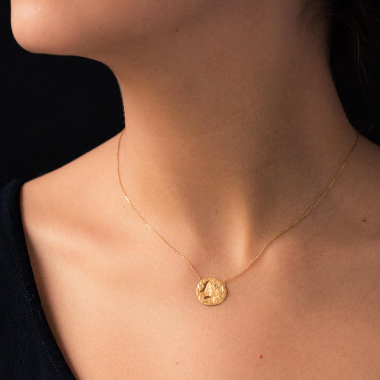 Pendant in 18 carats amati yellow gold, eagle's head hallmark.
Round in shape, this charming antique pendant represents the left profile of a woman with undone hair topped with a rose- cut diamond with an openwork floral decoration on one edge. The