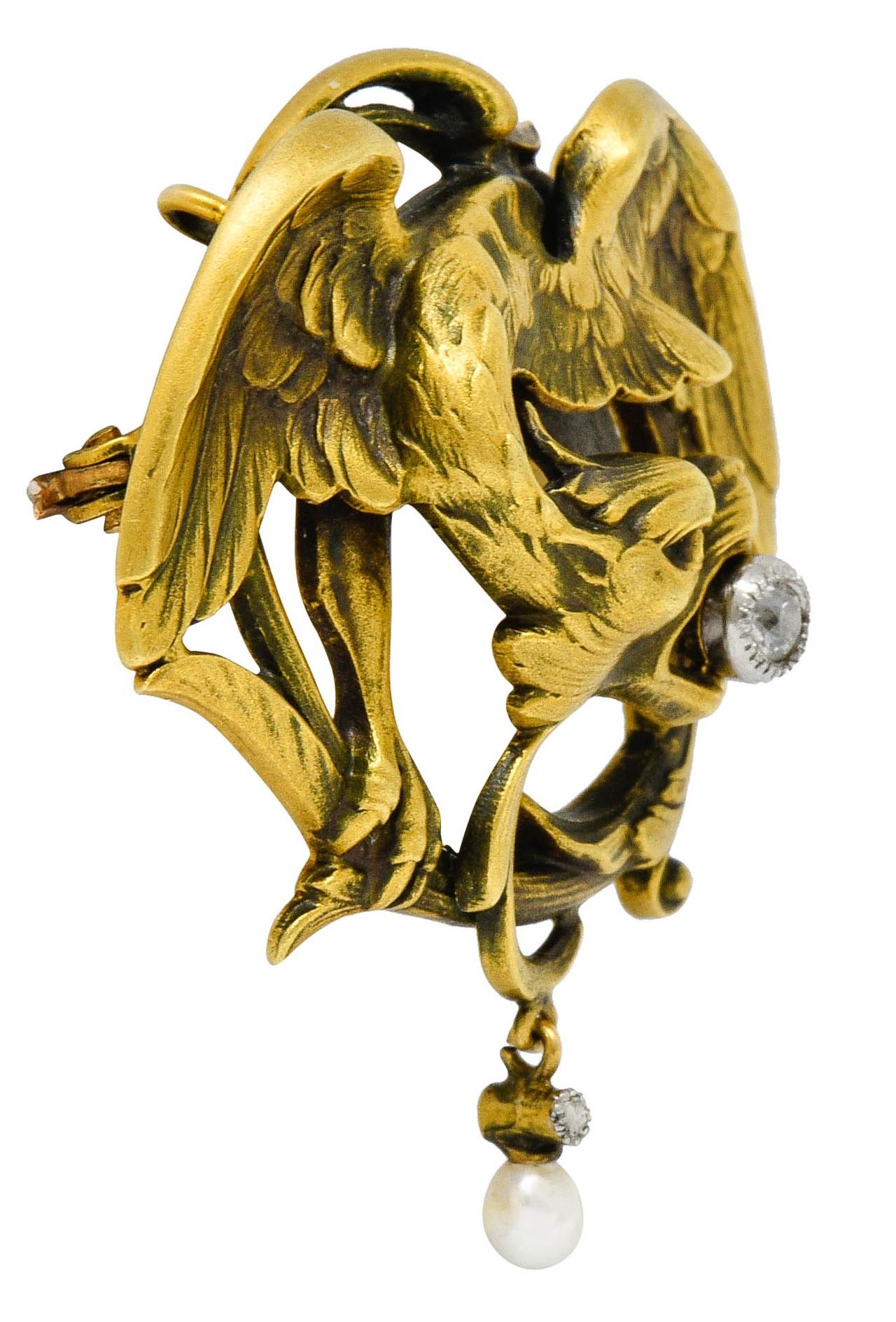 Circular brooch is designed as a highly rendered Griffin

With spread feathered wings, a whiplashed tail, and an old European cut diamond clutched in its beak

Bezel set in platinum and weighing approximately 0.10 carat; eye-clean

With an