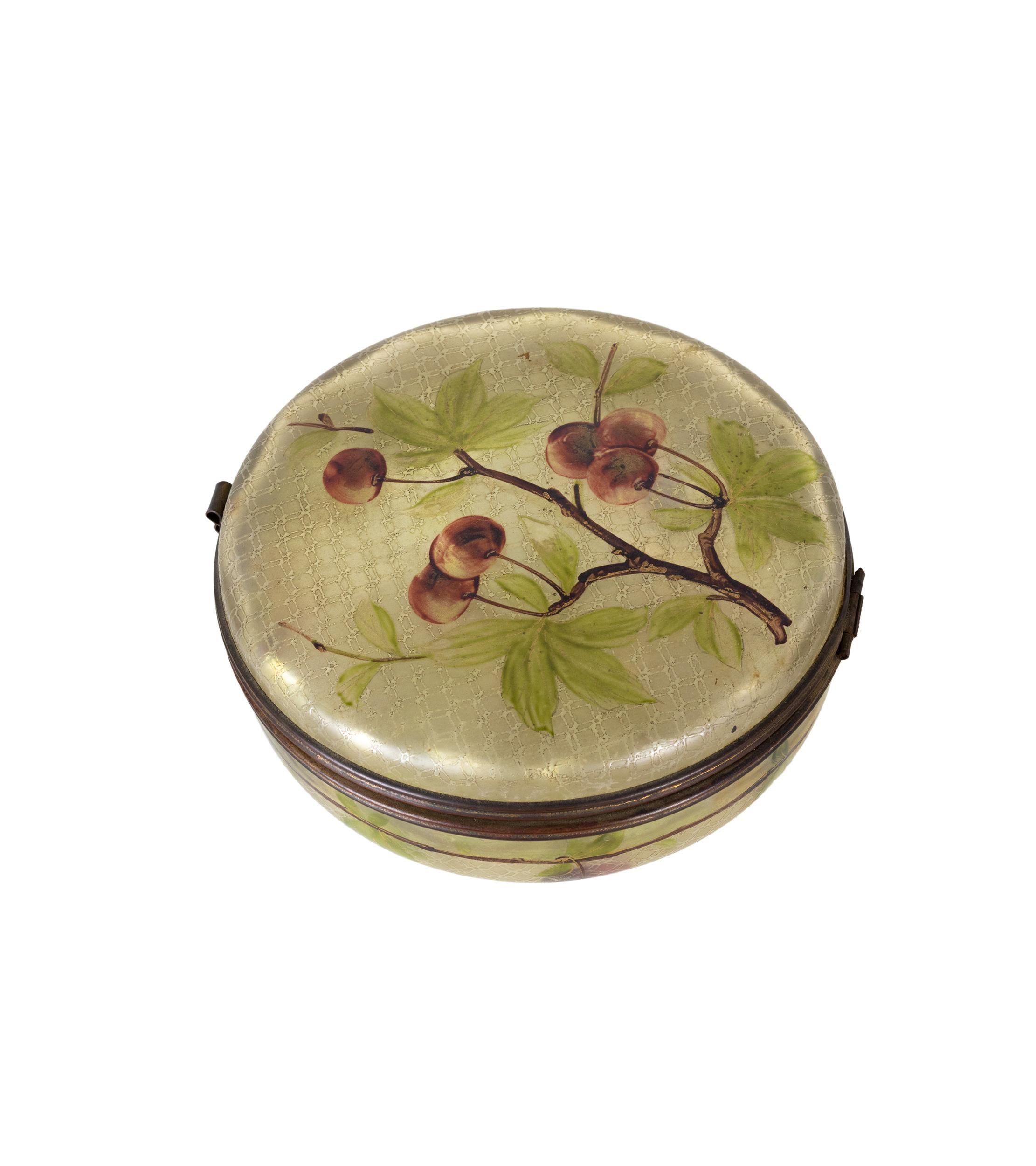 This early 20th-century Art Nouveau enameled glass trinket or jewelry box, adorned with a charming cherry and cherry tree design, showcases exquisite French hand decoration. Its brass hinged lid and intricate details add to its beauty.