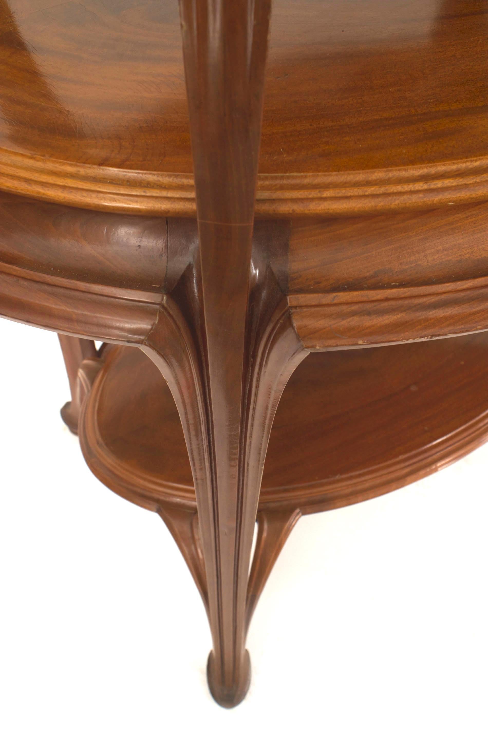 French Art Nouveau walnut three tier etagere table with oval top and shelves and carved floral trim corners.
