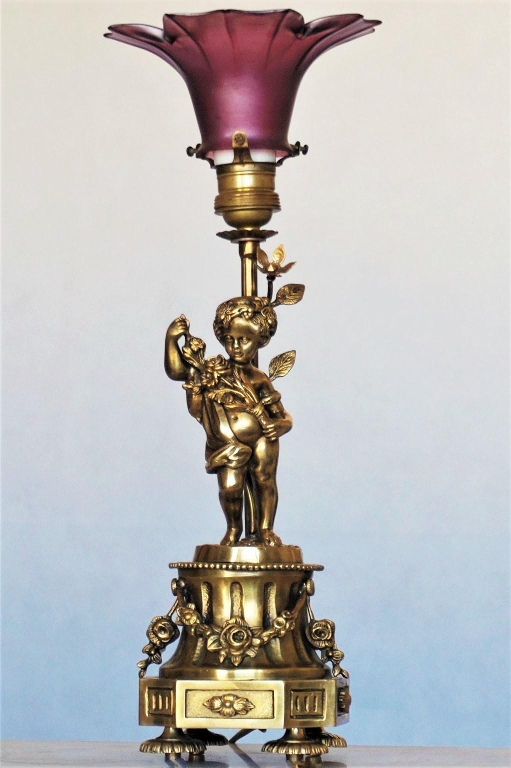 Heavy French Art Nouveau solid gilt bronze table lamp, cherub holding a branch of flowers, raised on richly ornate plinth base decorated with floral garlands, with purple vaseline glass tulip lampshade, 1910-1920.
One E-27 brass and porcelain light