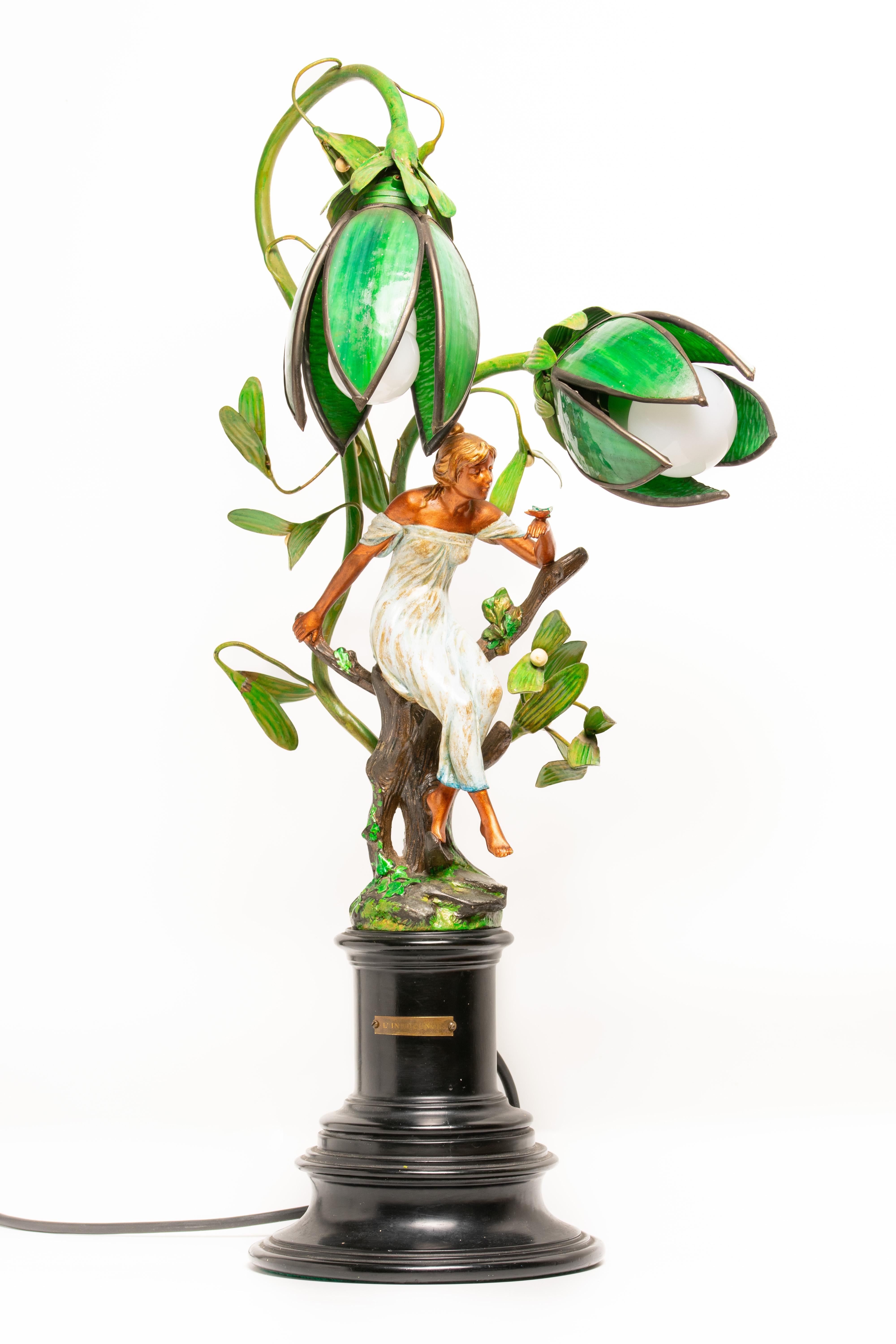 Diese figurale Art Nouveau-Lampe aus französischem Glas und Zinn stammt aus den frühen 1900er Jahren. Diese 55 cm hohe Lampe aus farbigem und patiniertem Zinn ist als weibliche Figur modelliert, die auf einem Baumstumpf sitzt und einen Schmetterling