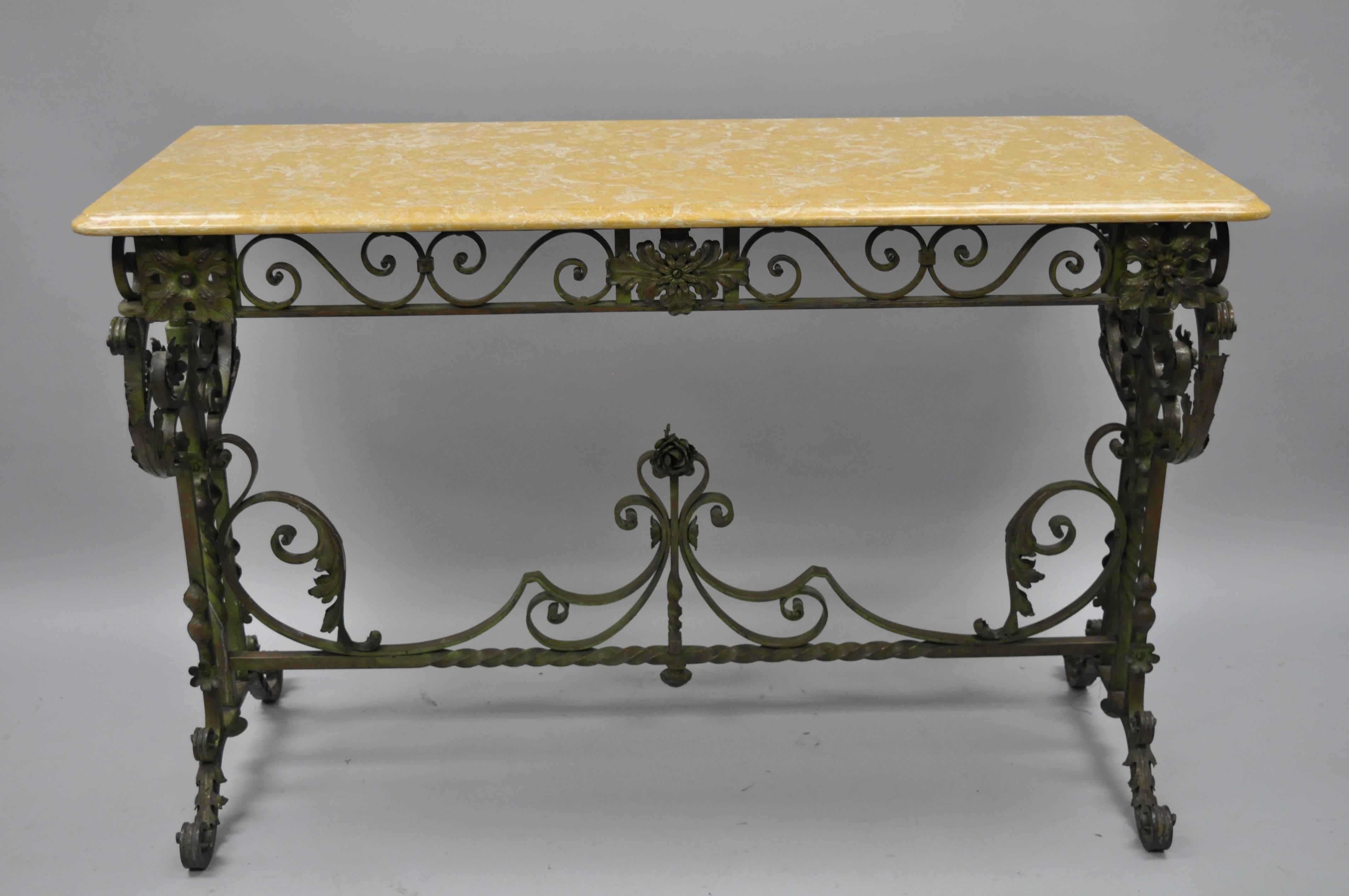 Antique French Art Nouveau scrolling wrought iron marble-top console table. Item features a patinated green scrolling wrought iron base with ornate floral work and stretcher support. The yellowish tan marble top features a beveled edge and rounded