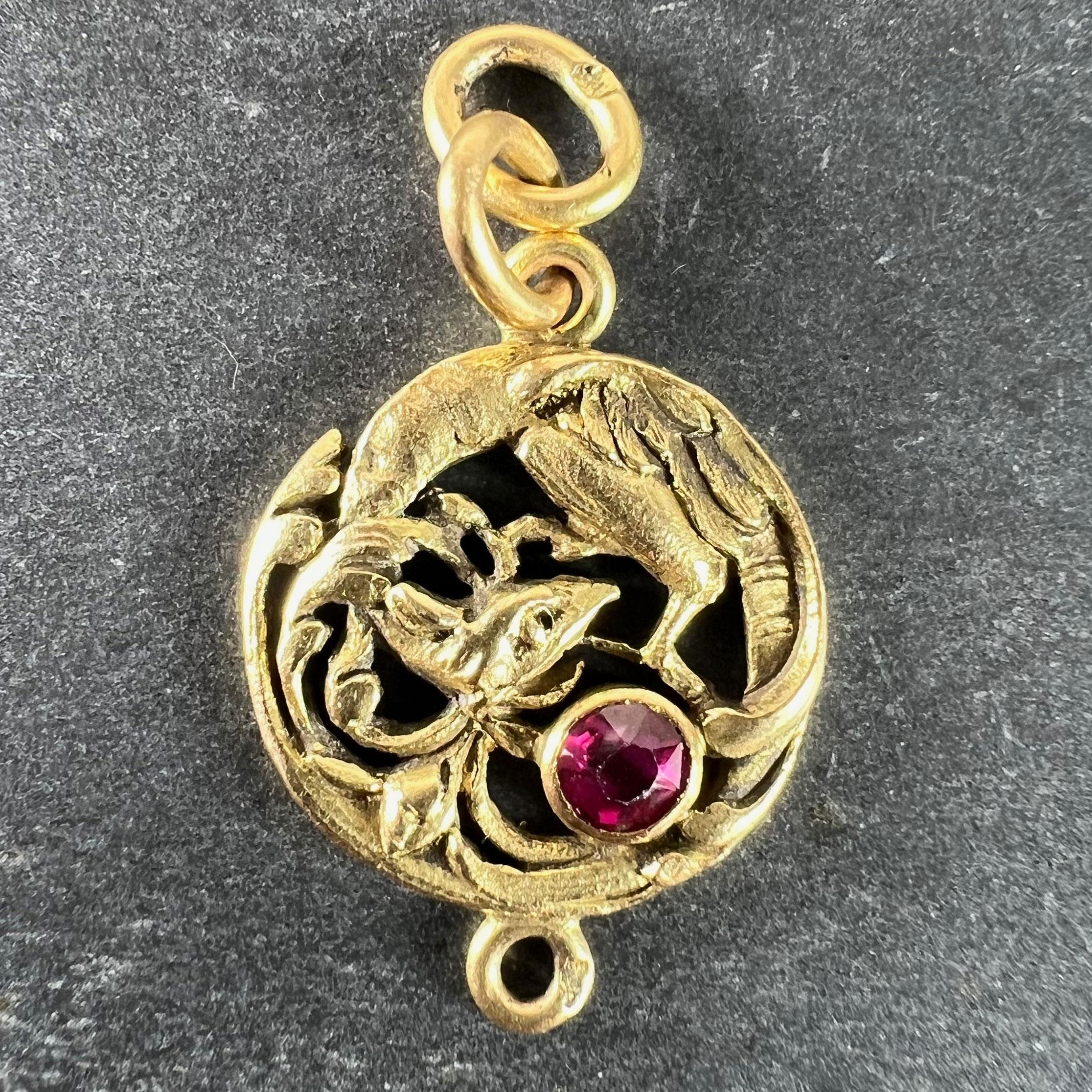 Un ciondolo charme francese in oro giallo 18 carati (18K) in stile Art Nouveau, disegnato come un grifone o una chimera accartocciata con un rubino rotondo. Il retro è inciso con piume e linee per raffigurare ulteriormente questa fantastica bestia.