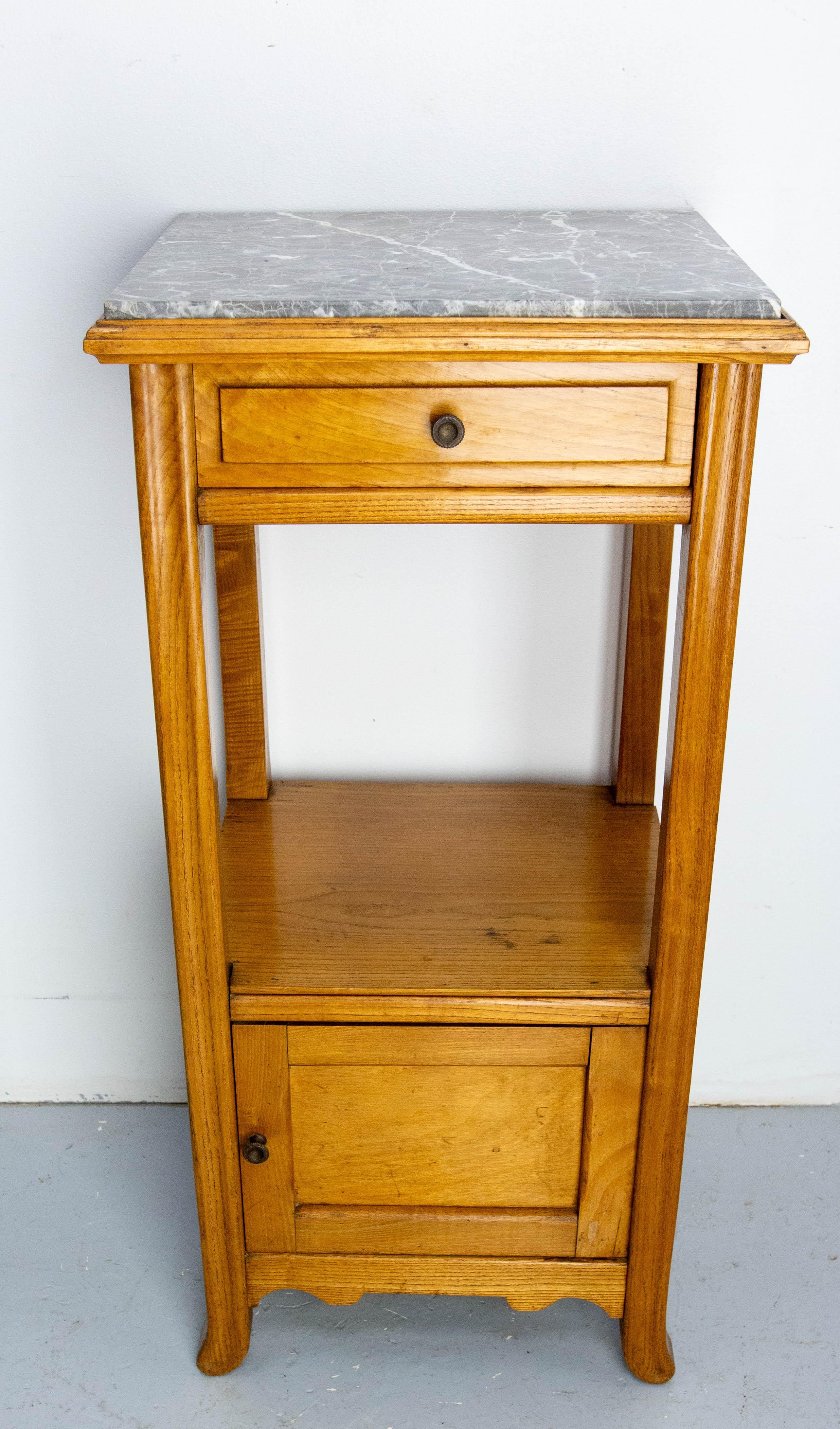 Pequeña mesa auxiliar alta o pedestal de recibidor con un cajón y un armario.
Forma típica del periodo Art Nouveau con sus pies curvados y sus patas delanteras  y la curvatura de sus patas.
Madera de fresno, mármol gris y botón de latón.
Este