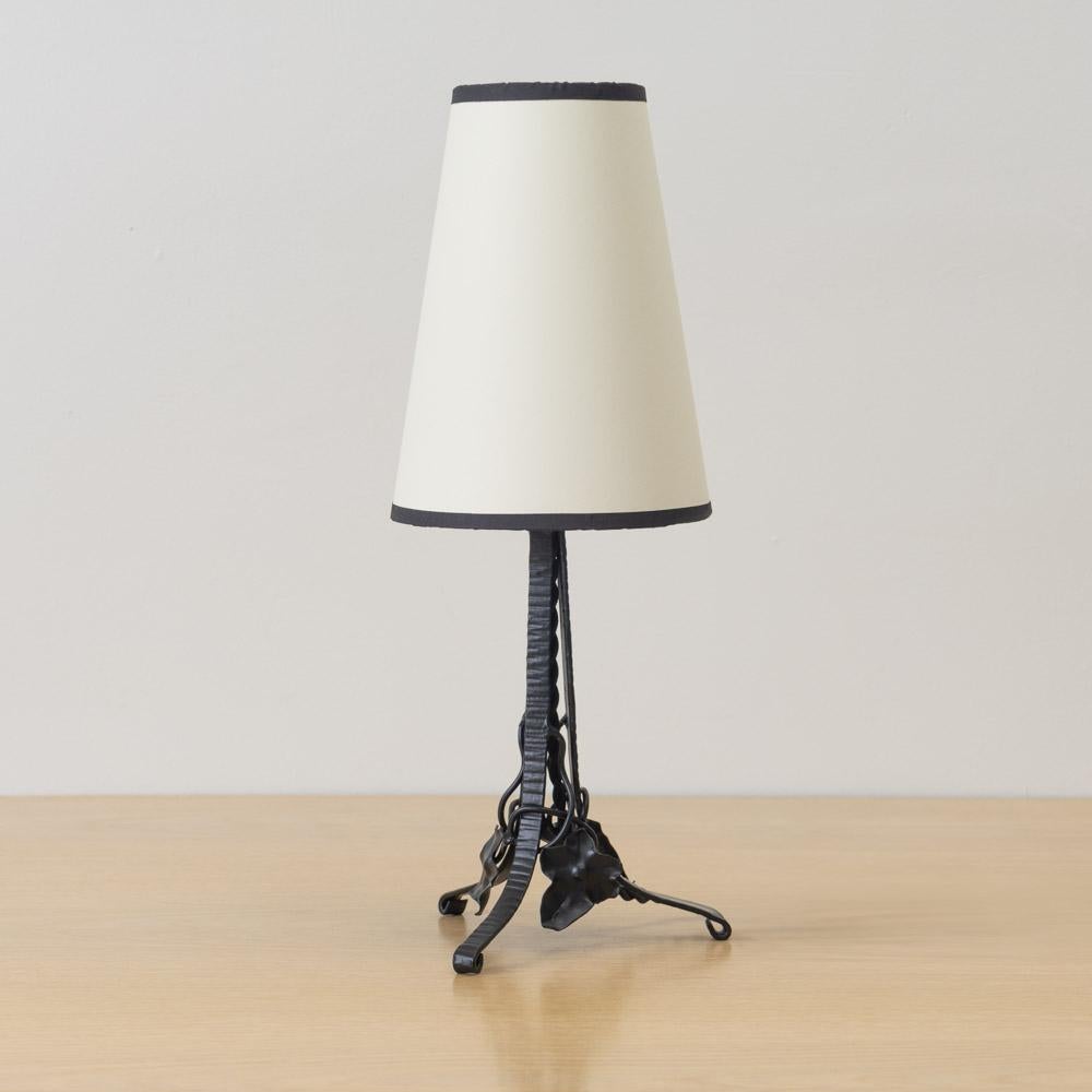 Incredibile e unica lampada da tavolo francese Art Nouveau in ferro. Corpo in ferro forgiato con foglie fluttuanti su una base in ferro a treppiede. Cablata di recente con un nuovo paralume affusolato in carta color crema con finiture nere. Il ferro