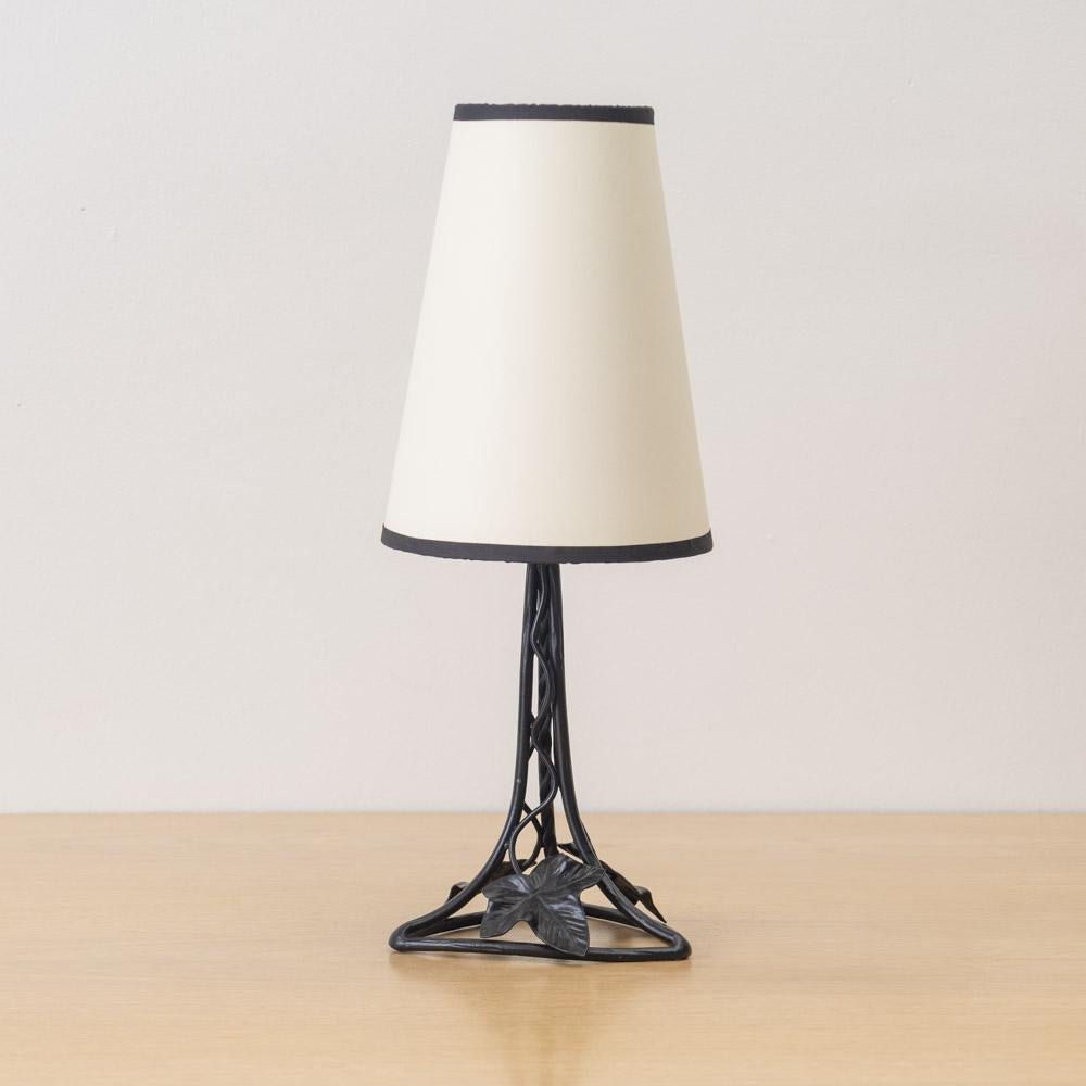 Incredibile e unica lampada da tavolo francese Art Nouveau in ferro. Corpo in ferro forgiato con foglie fluttuanti su una base triangolare in ferro. Cablata di recente con un nuovo paralume affusolato in carta color crema con finiture nere. Il ferro
