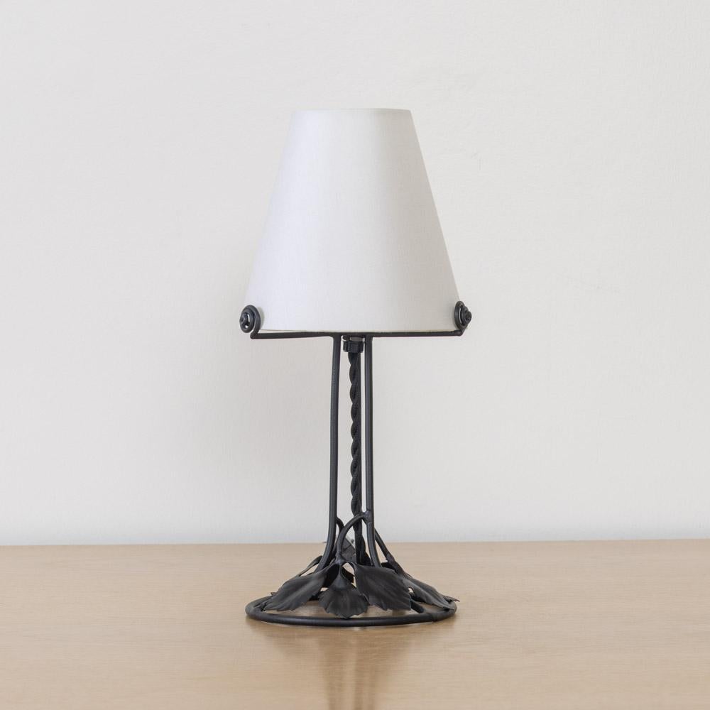 Incroyable et unique lampe de table en fer Art Nouveau français. Corps en fer forgé avec détails de feuilles flottantes sur une base circulaire en fer. Nouvellement recâblée avec un nouvel abat-jour en lin effilé. Le fer a été récemment recouvert