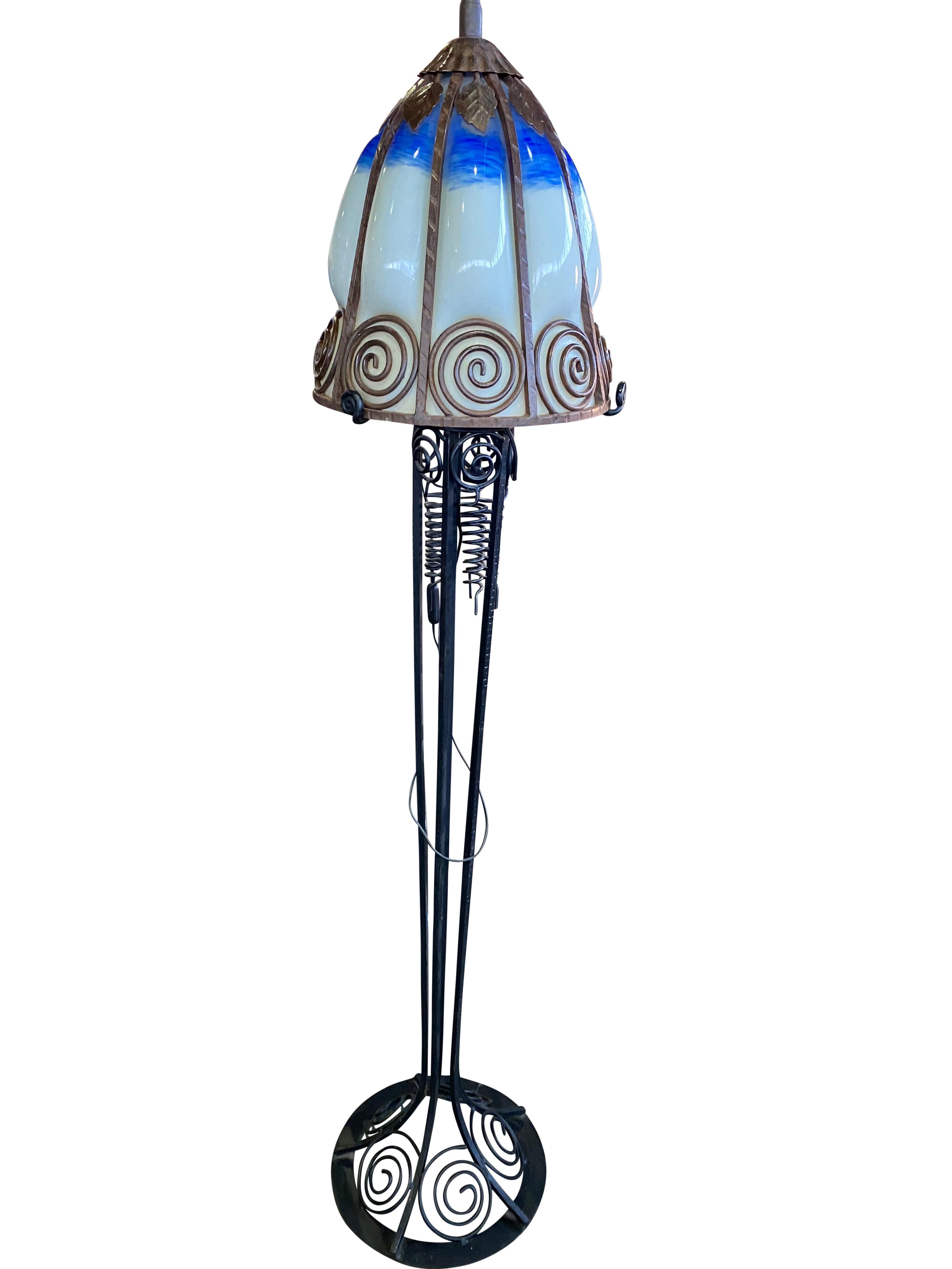 A wonderful French Art Nouveau standard lamp, 20th century. The stands are handmade in wrought iron with black finish patina and hammered with floral pattern. The metalwork is of excellent quality.
Crowned with bright colored shades in mottled