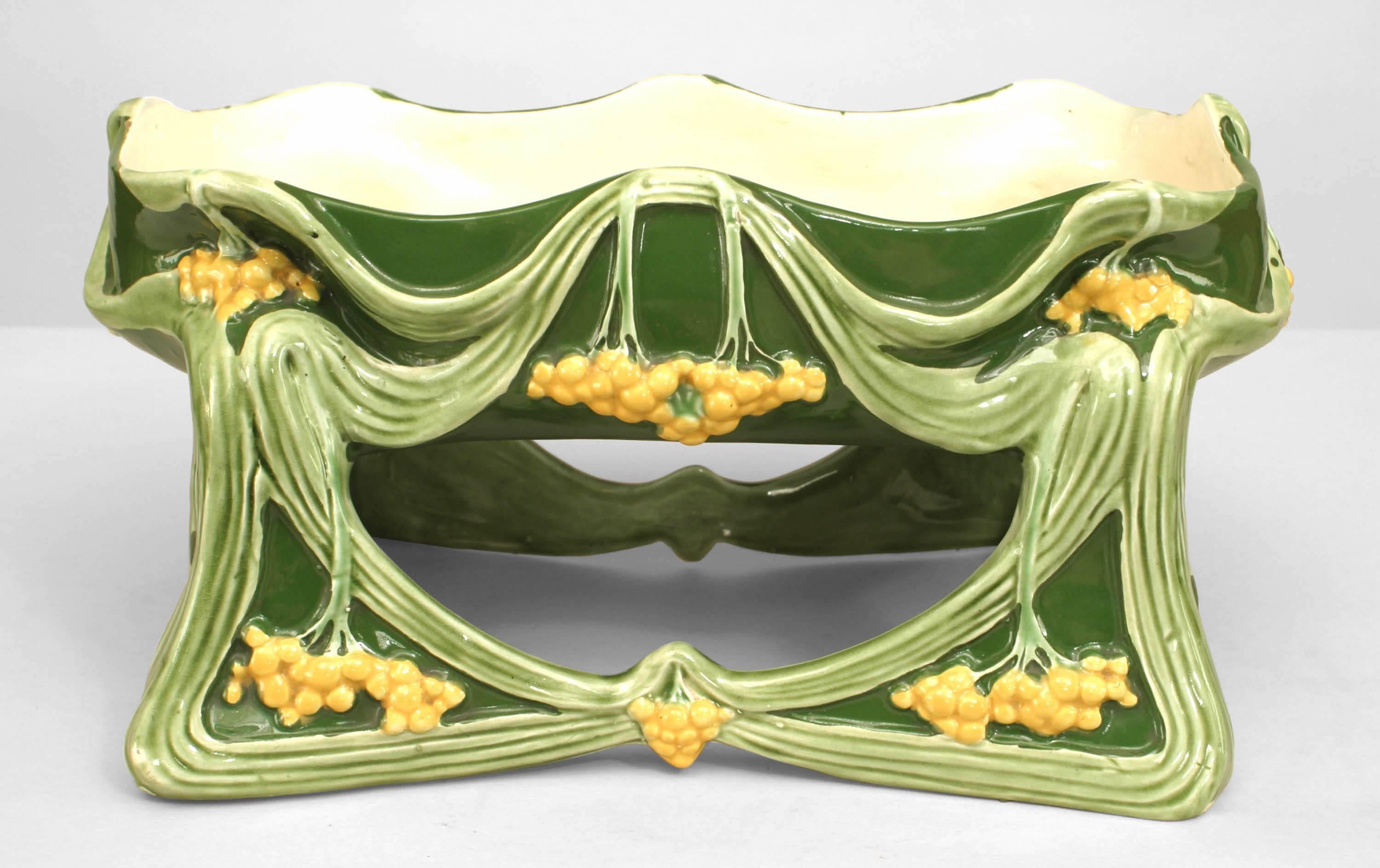 French Art Nouveau light and dark green porcelain rectangular shaped centerpiece with yellow floral trim and raised on an open base.
