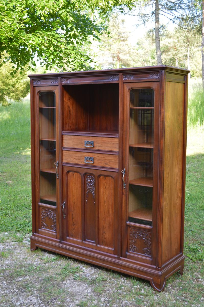 - Art Nouveau French bookcase. 
- Circa 1910, designed and made by Gauthier-Poinsignon. 
- Solid mahogany and veneered. 
- Carved floral motif (e.g. brambles, clematis). 
- Bevelled windows. 
- Bronze handles.
- Two side windows & arched glass