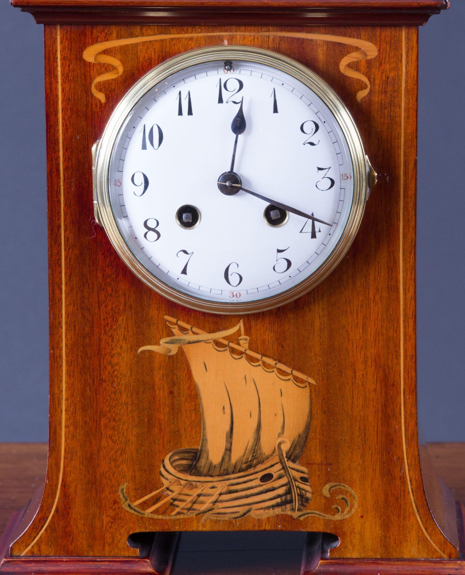 French Art Nouveau mahogany cased mantel clock with arch top above satinwood inlay depicting a Viking longboat at full sail.
Enamel dial with Arabic numerals. Eight day movement signed ‘Couillet Freres’ striking the hours and halves on a coiled