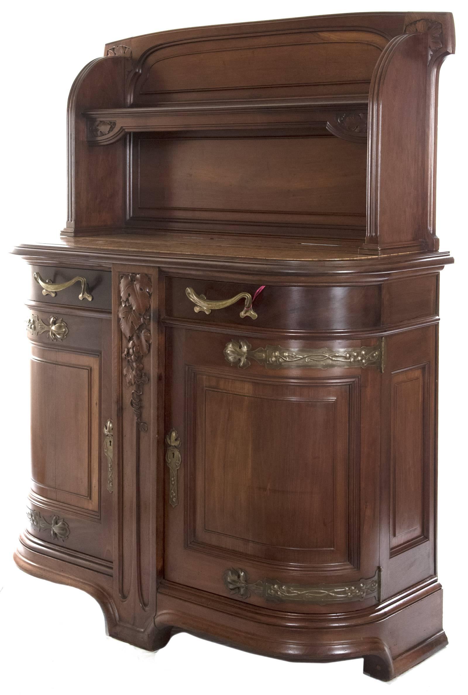 A French Art Nouveau mahogany sideboard in the style of Louis Majorelle in the early 20th century. An open shelf decorated with leaf motifs is raised between two curved side panels, above a marble-inset top with a stepped edge above a base of