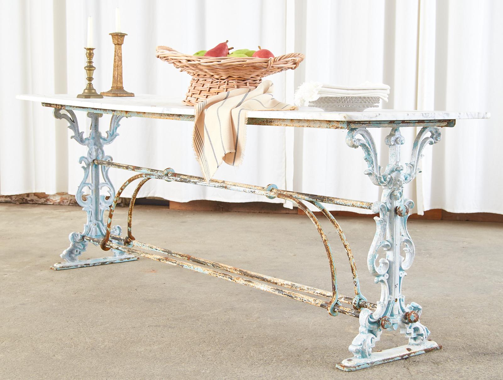 Fantastic French Art Nouveau patisserie or pastry table featuring a weathered, smooth Carrara marble top. The late 19th century/early 20th century table is hand-crafted with a trestle style base. The decorative legs have acanthus scroll detail