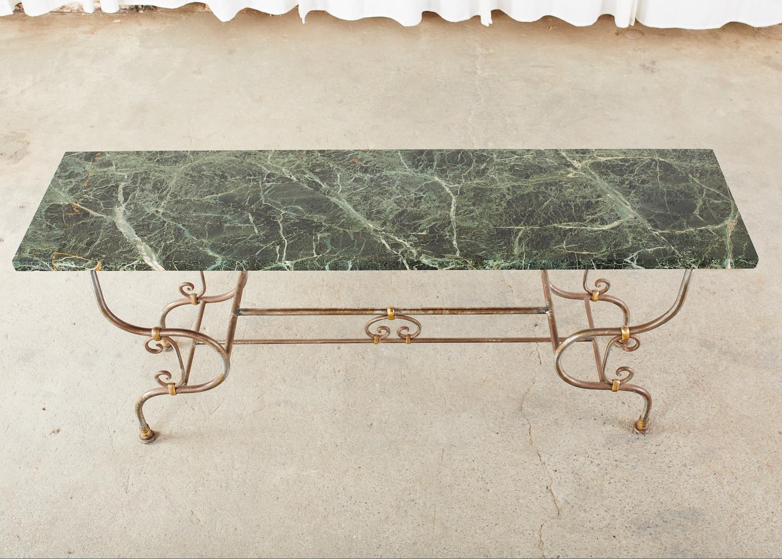 Fantastic French Art Nouveau pastry table or console table featuring a dark green marble slab top. The thick marble is supported by a bronze mounted steel decorative arts base with whimsical scroll work and a beautiful profile. The base measures 66