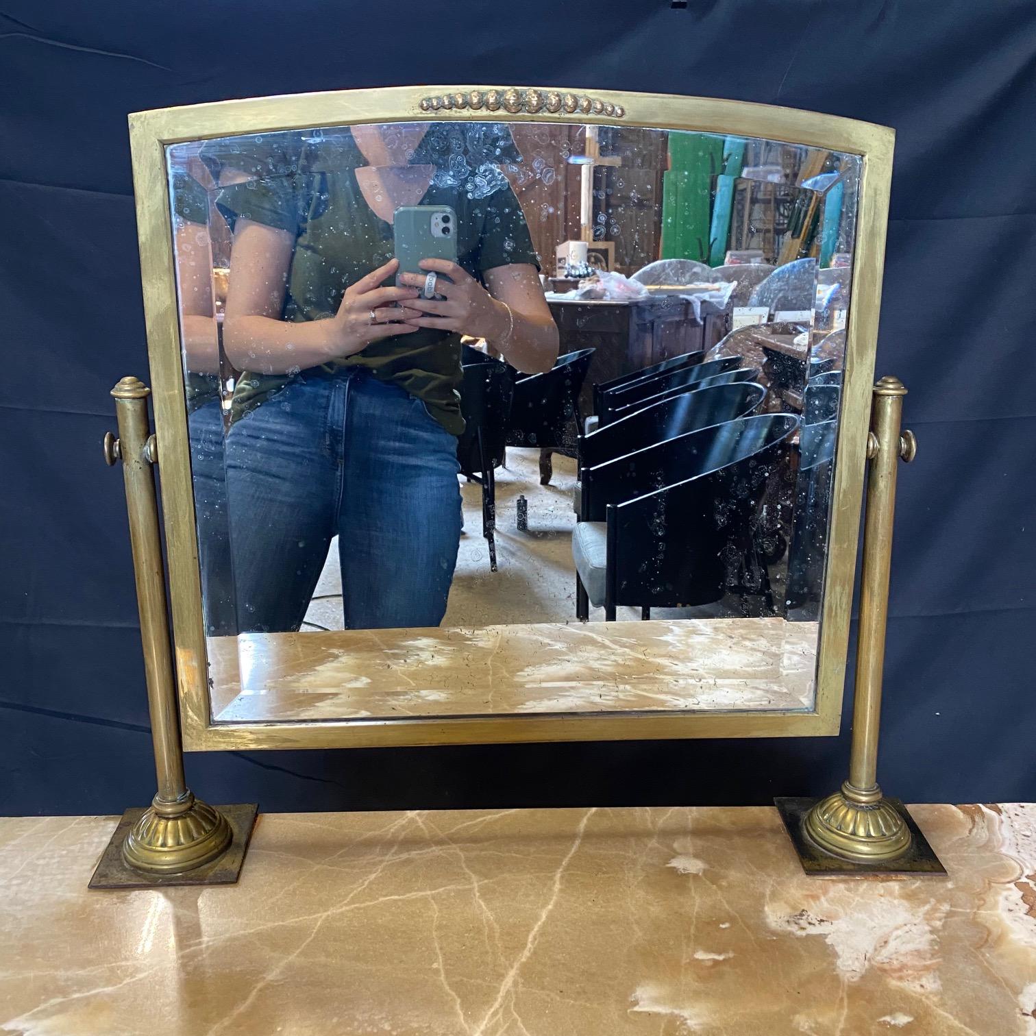 Really beautiful marble on this unusual French dressing table or vanity from the early 20th century. Beveled original mirror is held by beautiful brass supports, matched by gorgeous sculpted brass legs upon original casters. One drawer inside wooden
