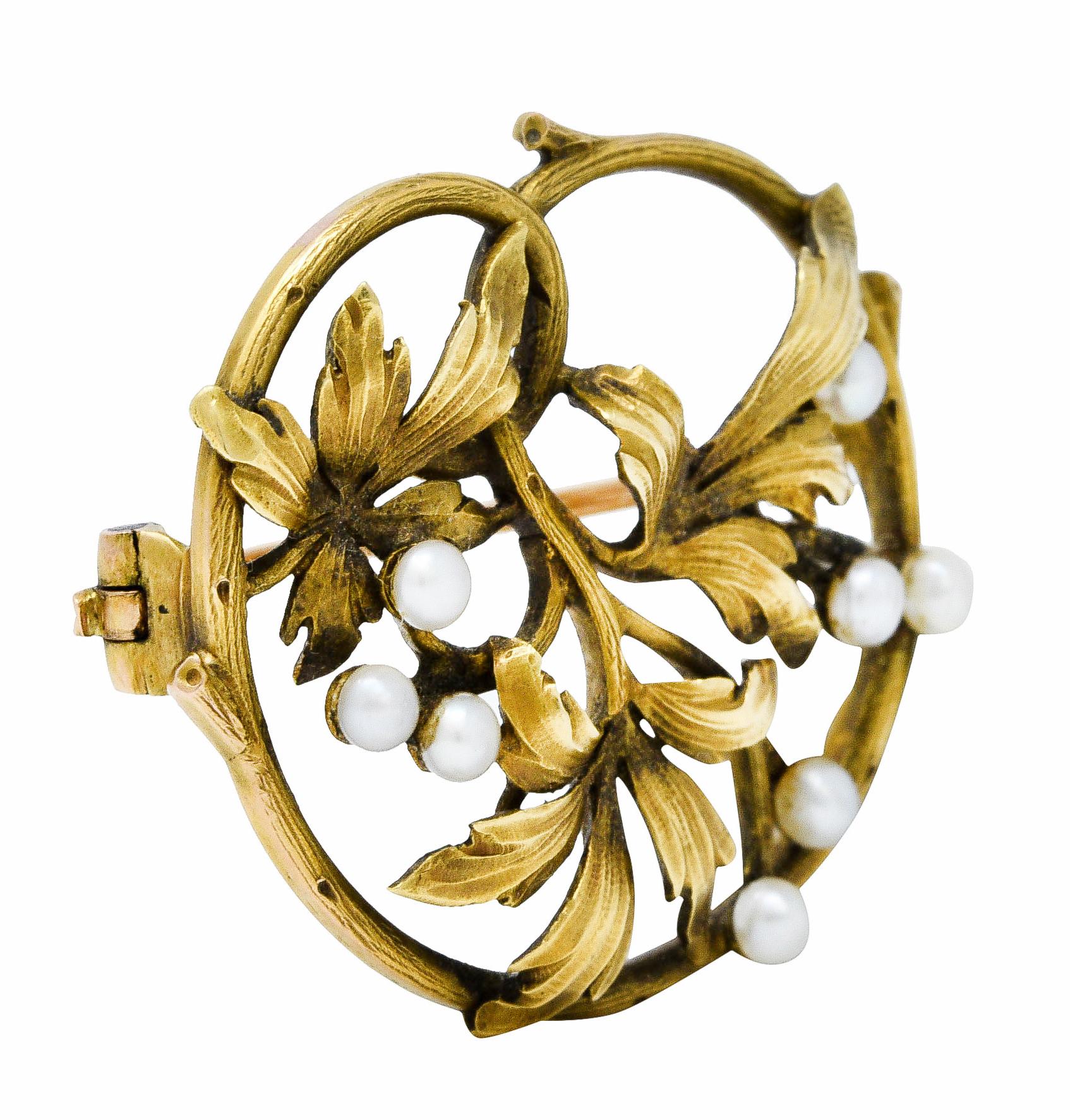 Circular brooch is comprised of a winding stem an three dynamically rendered ivy leaves

Accented by 2.5 mm white pearls with moderate to strong iridescence

Completed by a pin stem with closure

With maker's mark and French assay mark for 18 karat