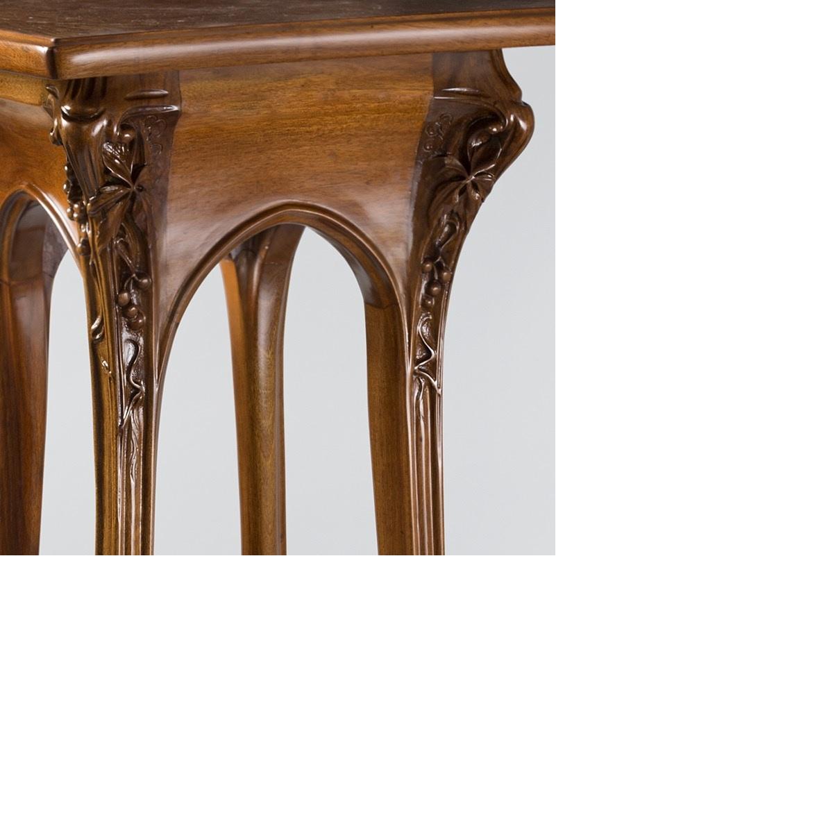 A French Art Nouveau walnut three-tiered pedestal by Louis Majorelle, featuring a rotating tray on the top. Leaves and berries adorn the upper portion of the legs. The gently curving legs are also deeply carved, circa 1900. 

Firmly rooted in the