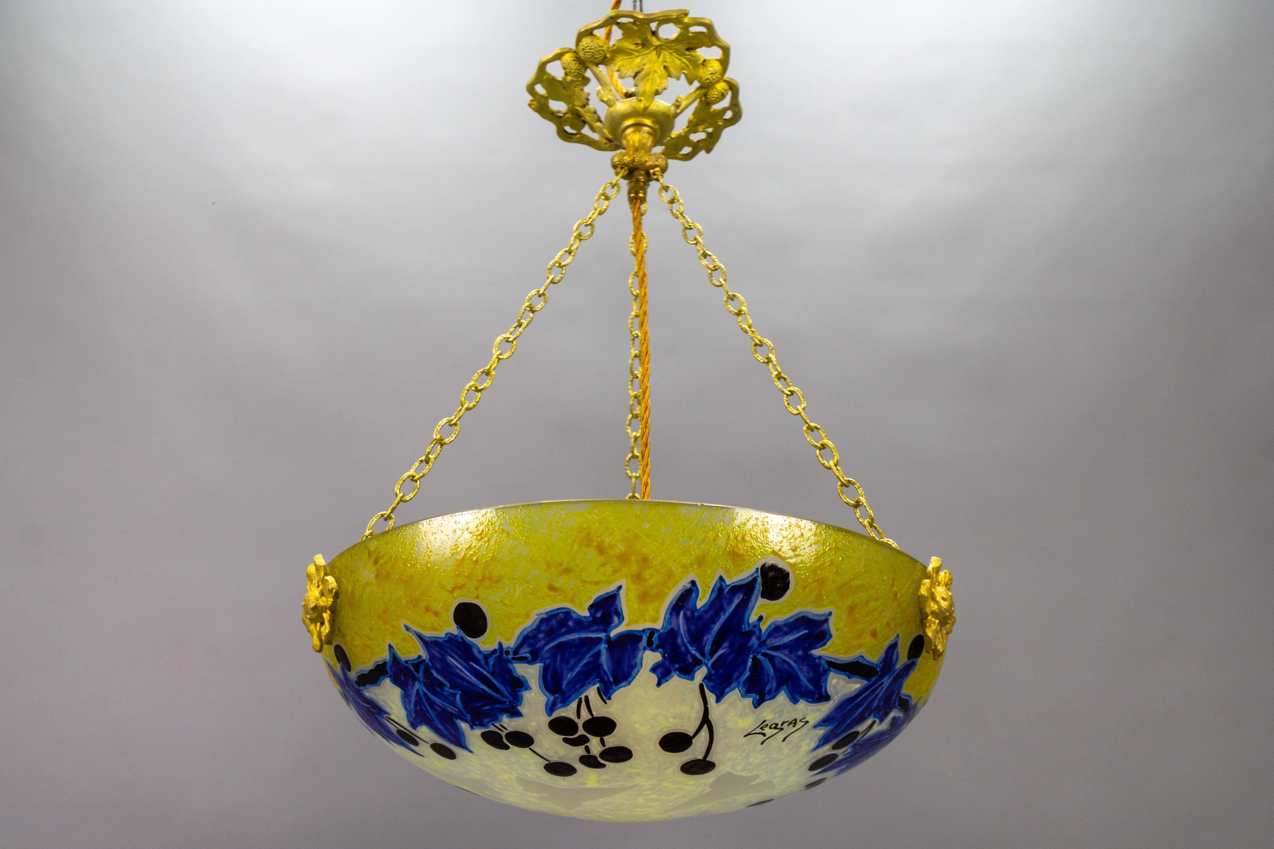 French Art Nouveau pendant light with yellow and blue glass and ivy motifs signed Legras, circa 1920.
This gorgeous Art Nouveau period pendant light features a frosted glass bowl with enameled hand-painted stylized ivy leaves and fruits in blue,