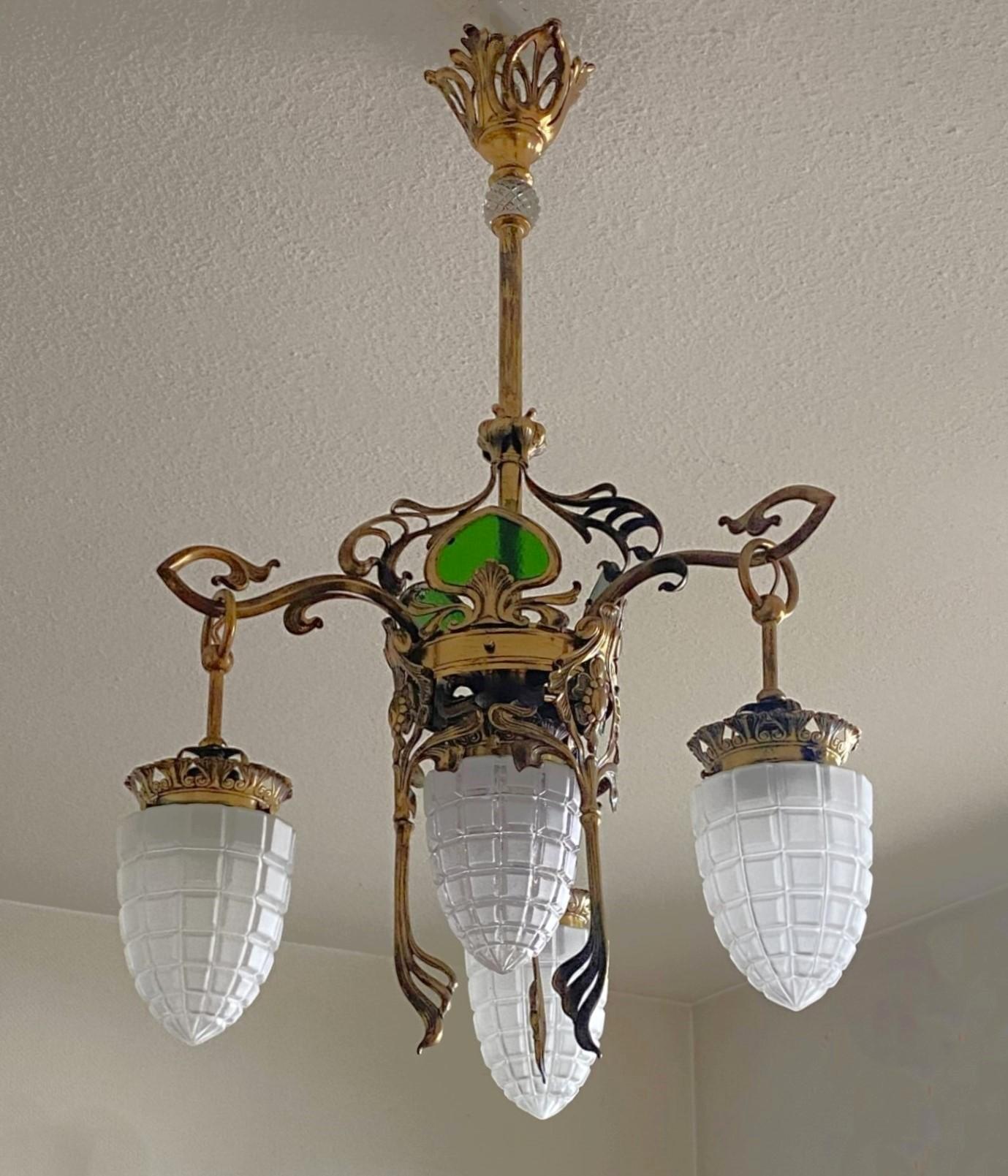 One of kind Art Nouveau period brass and cut glass four-light chandelier, France, 1900-1910. Richly elaborate gilt brass  with wonderful detailing and green glass panels adorning each side, three side and one central lamp arms with four frost-cut