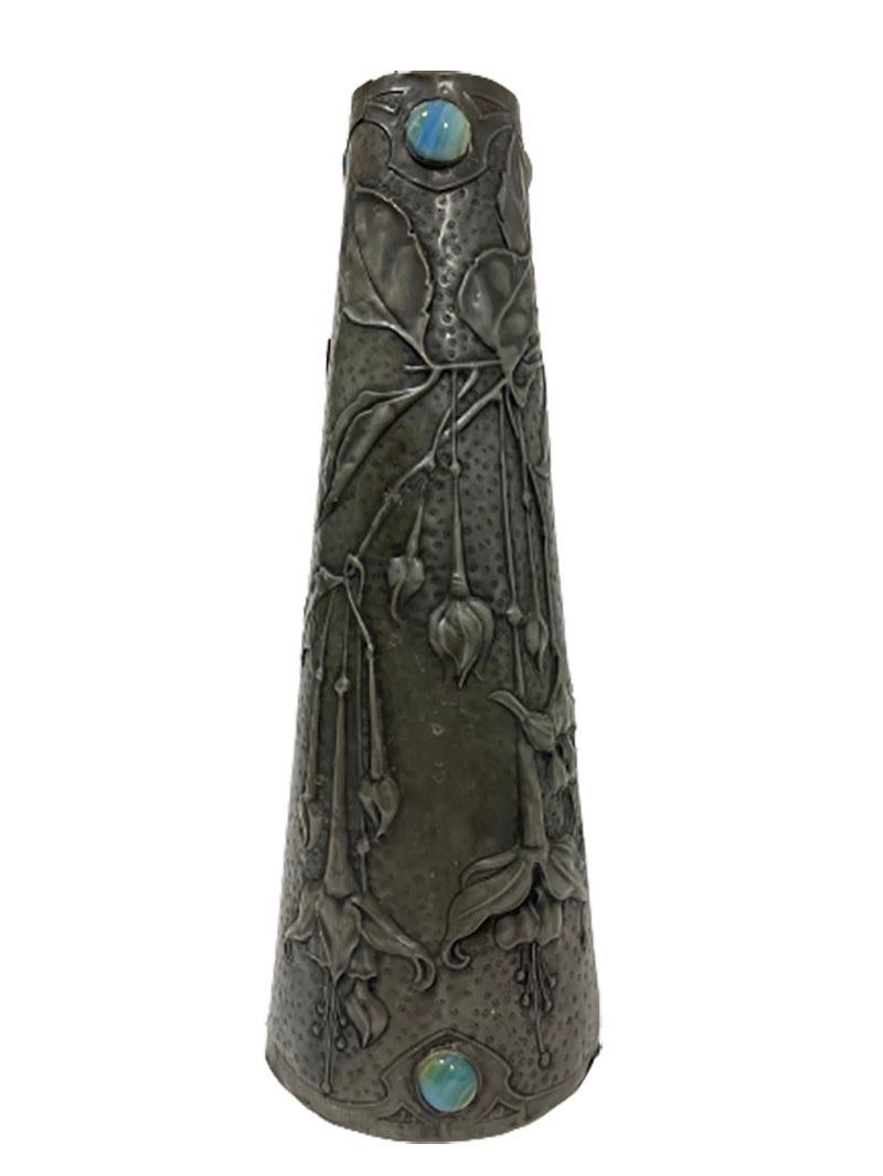 French Art Nouveau pewter vase

A pewter vase with flowers and an insect in Art Nouveau style with stones in blue, green striped glass. 
The vase is hand made and has an overlay (folded around). 
The vase is of French origin around 1900

The