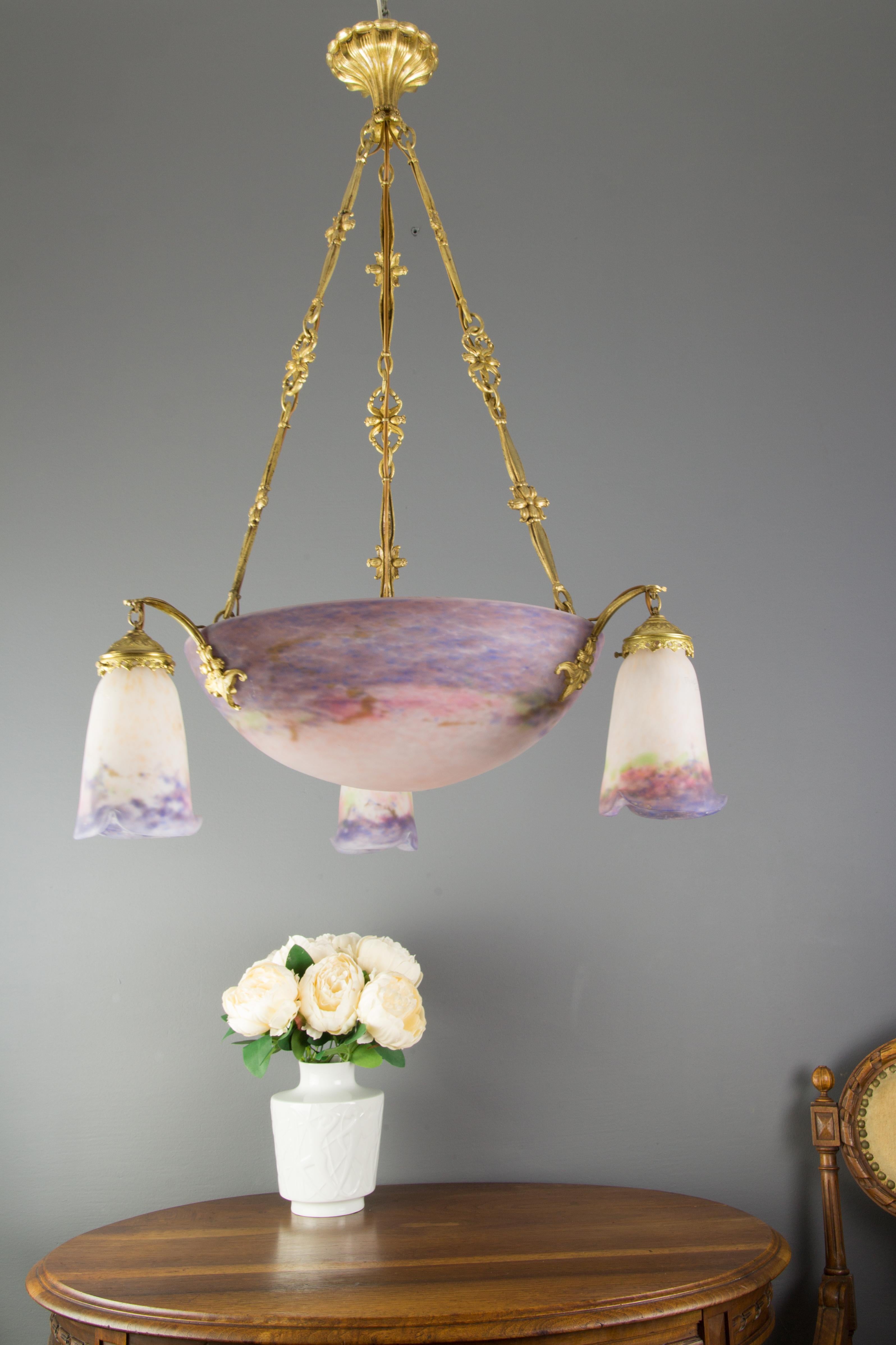 Superb French chandelier by the Muller Frères brothers, from circa the 1920s, consisting of a large (40 cm / 15.74 in) purple and white central glass bowl shade and three surrounding shades, made in “Pâte de Verre” technique. Each glass shade is