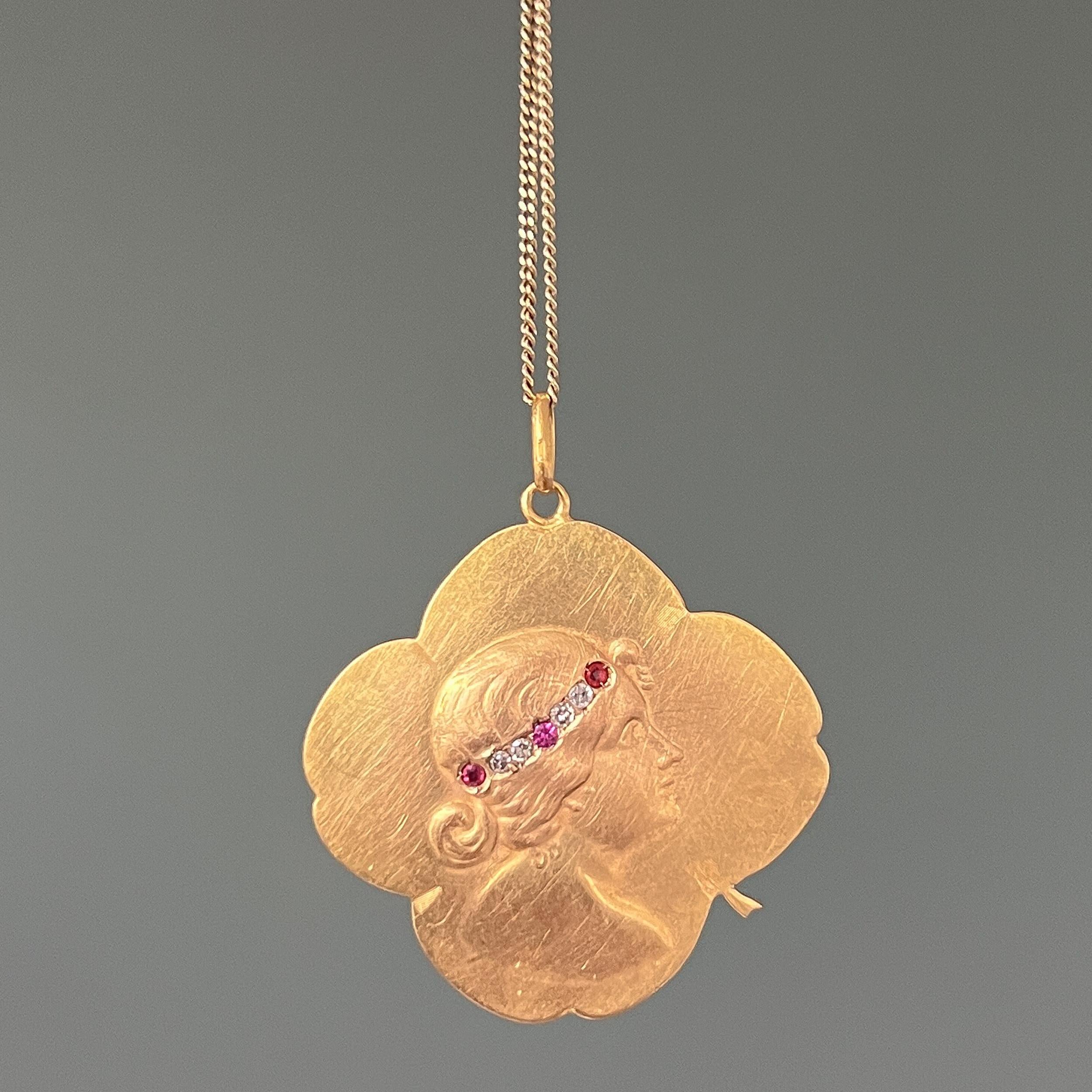 This antique four-leaf clover pendant dates back to the Art Nouveau movement, 1890-1914. The lovely four-leaf clover shape pendant is created in 20 karat yellow gold depicting a female portrait in a bass-relief profil. She is wearing a headband