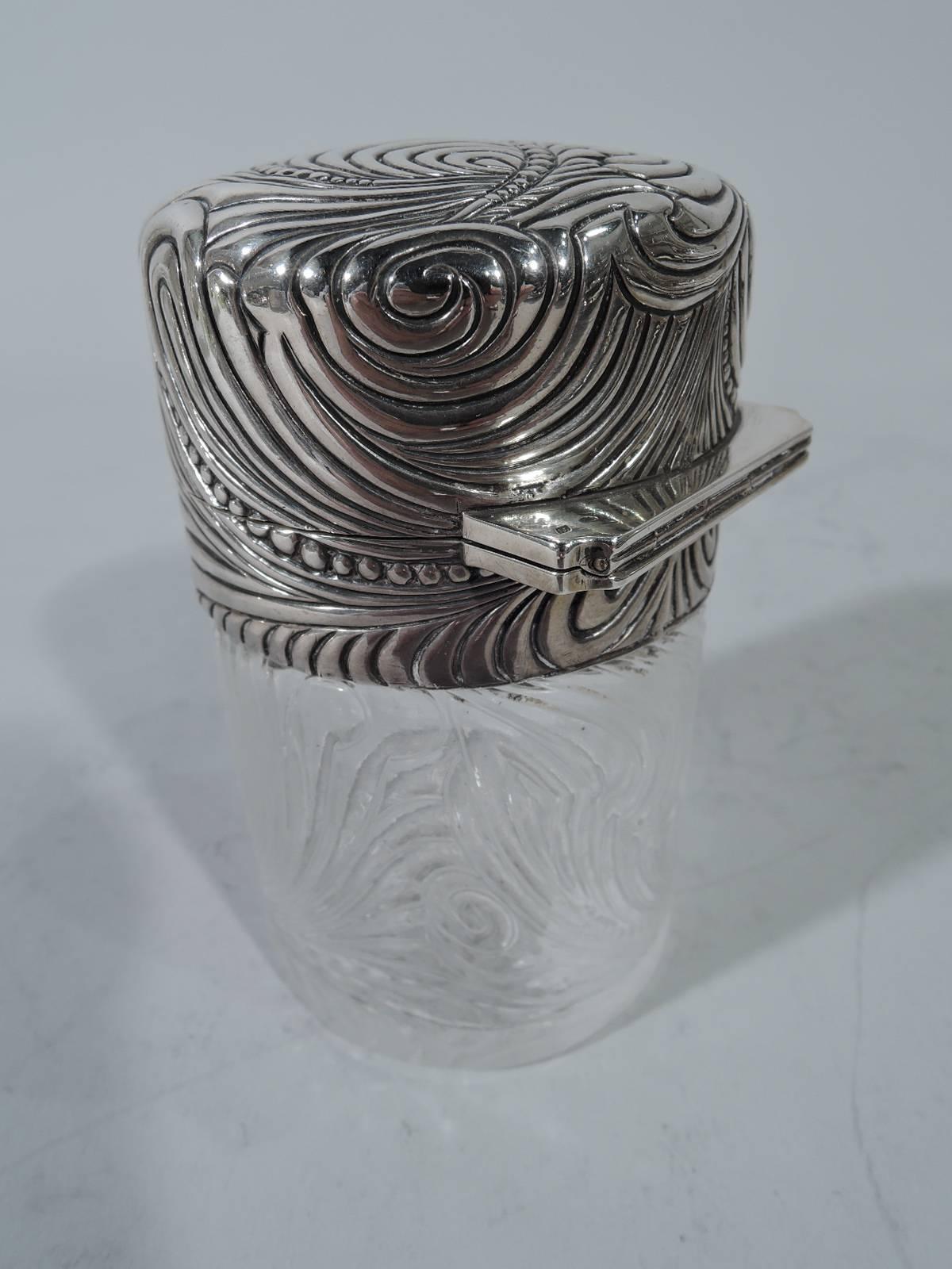 Art Nouveau silver and crystal vanity jar. Retailed by Tiffany & Co. in Paris. Cylindrical clear glass and silver collar with hinged cover. Interior stopper with short plug. Dense swirling and fluid scrollwork heightened with beading. French marks