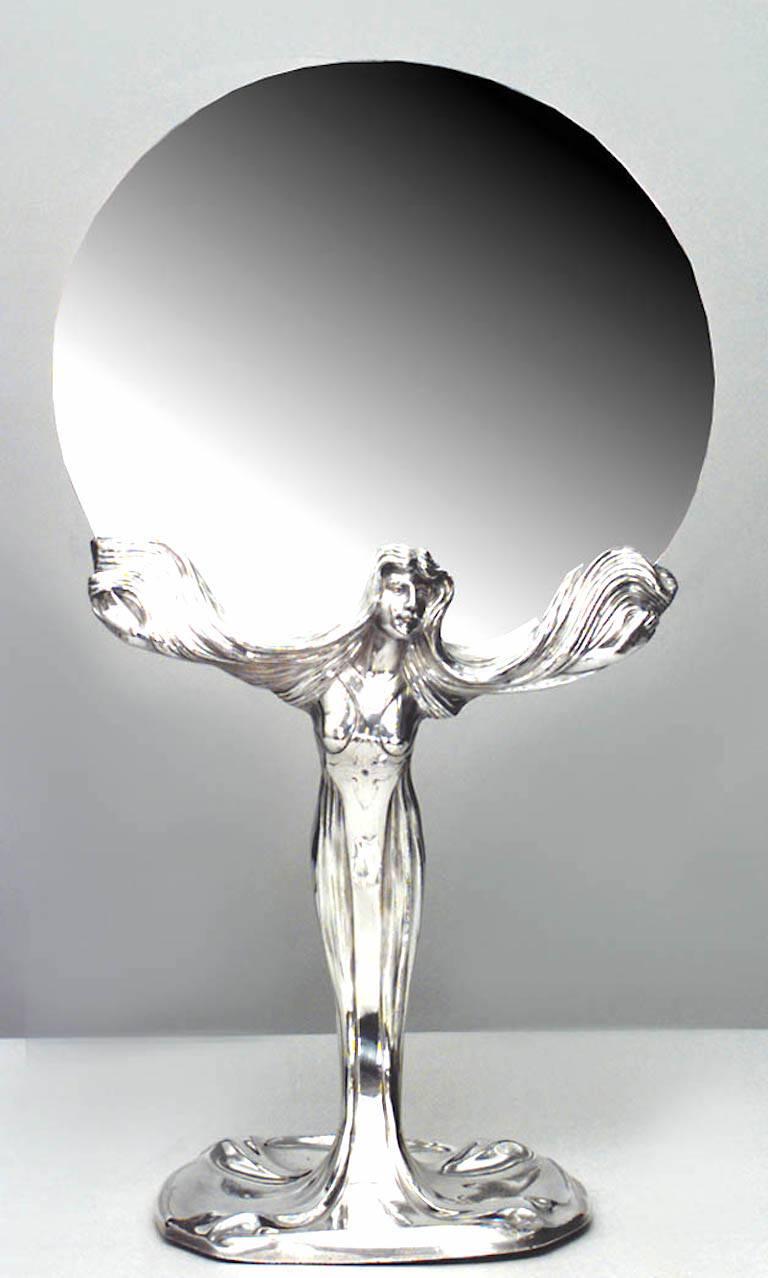 Table de toilette / miroir de courtoisie Art Nouveau en métal argenté, avec un motif figuratif et une base ronde à piédestal.
