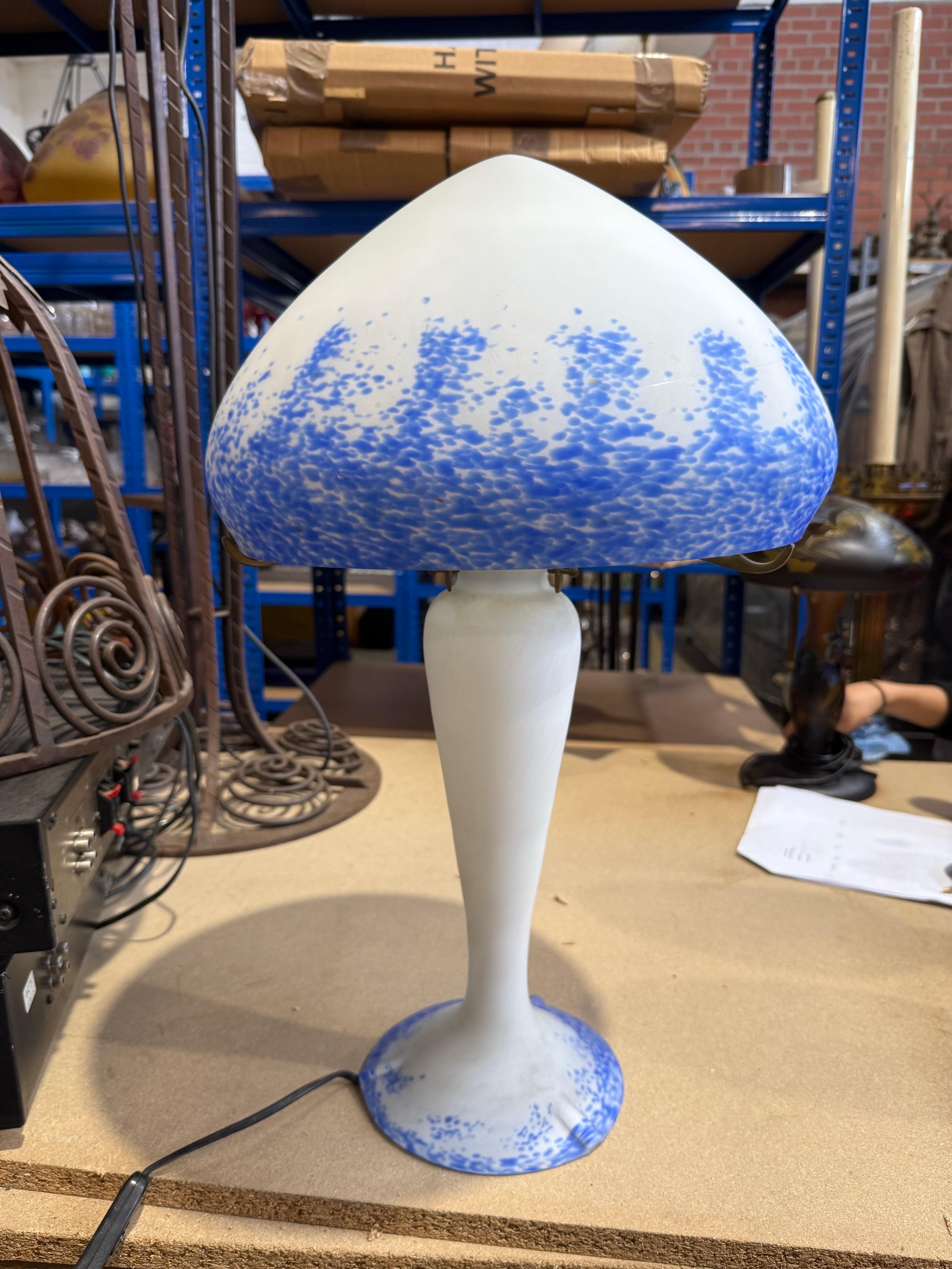 Una elegante lámpara de sobremesa de estilo Art Nouveau francés que presenta una armoniosa fusión de tonos blanco cremoso y azul cobalto moteado. Fabricada en vidrio grabado al ácido, la lámpara presenta una pantalla en forma de seta que fluye con