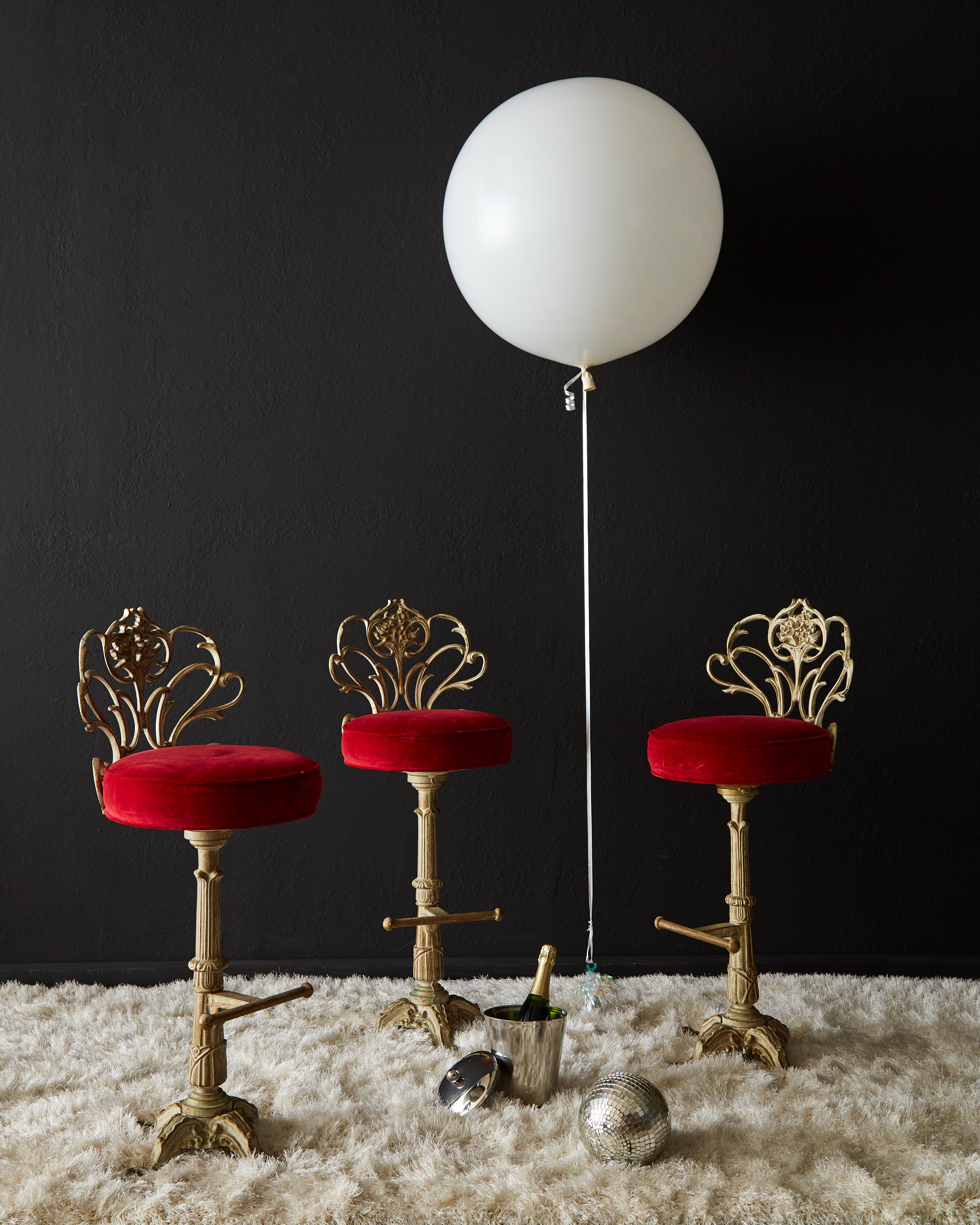 Spectacular set of three cast iron bar stools made in the French Art Nouveau style. Featuring an artistic floral backrest with a red velvet covered swivel seat. Supported by a decorative column ending with four legs and having a footrest. The iron