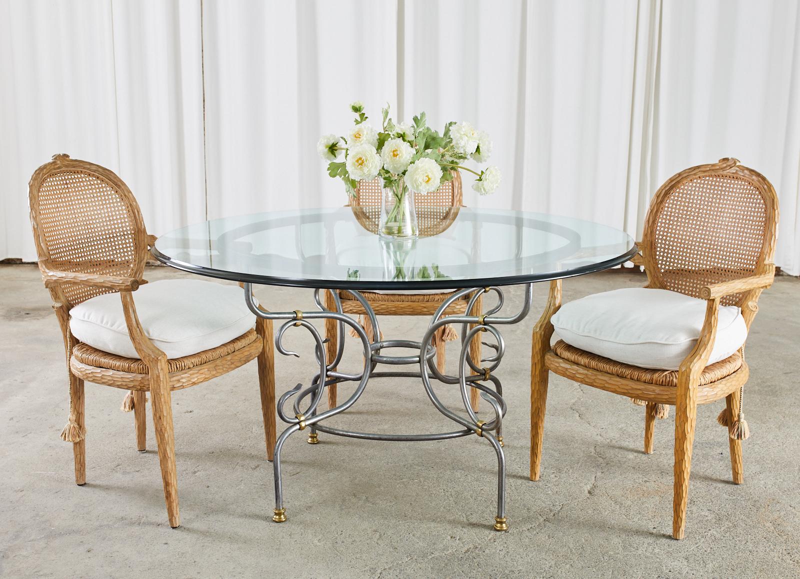 Attractive French polished steel patio and garden dining table with bronze mounts. The table features a steel base with gracefully curved legs conjoined by round stretchers and scrolls. The base has a beautiful finish with a nickel like patina and