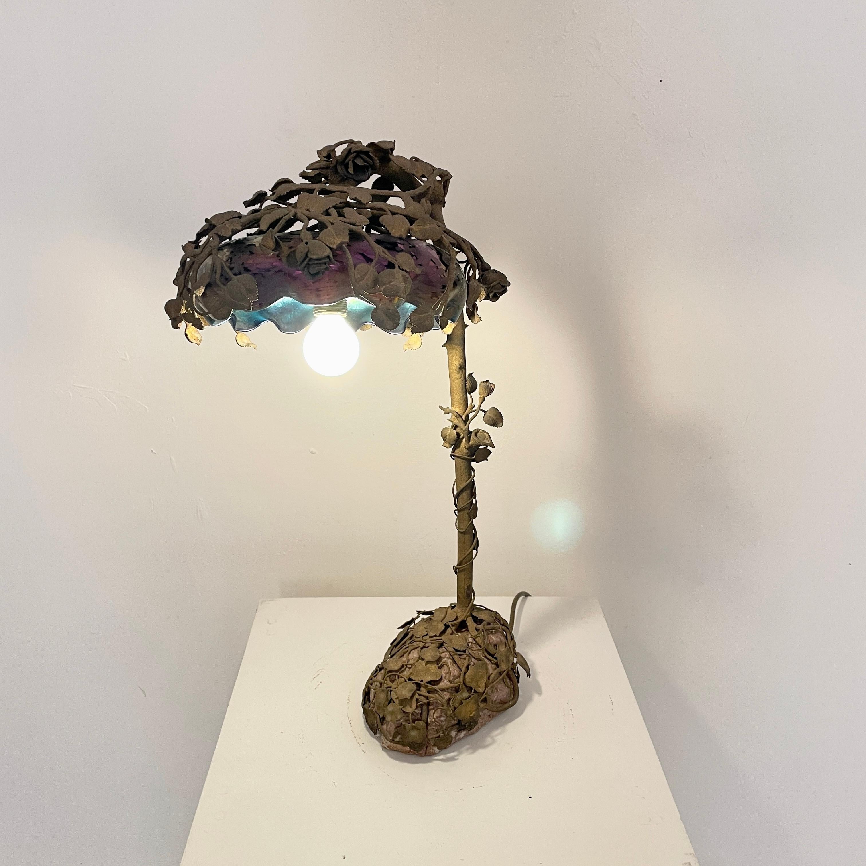 Diese ausgefallene und sehr seltene französische Jugendstil-Tischlampe mit Blumenmuster wurde um 1910 in Paris hergestellt. 
Sie ist aus Bronze gegossen und zeigt einen Rosenstrauch auf einem echten Steinsockel. Der Lampenschirm ist aus emailliertem