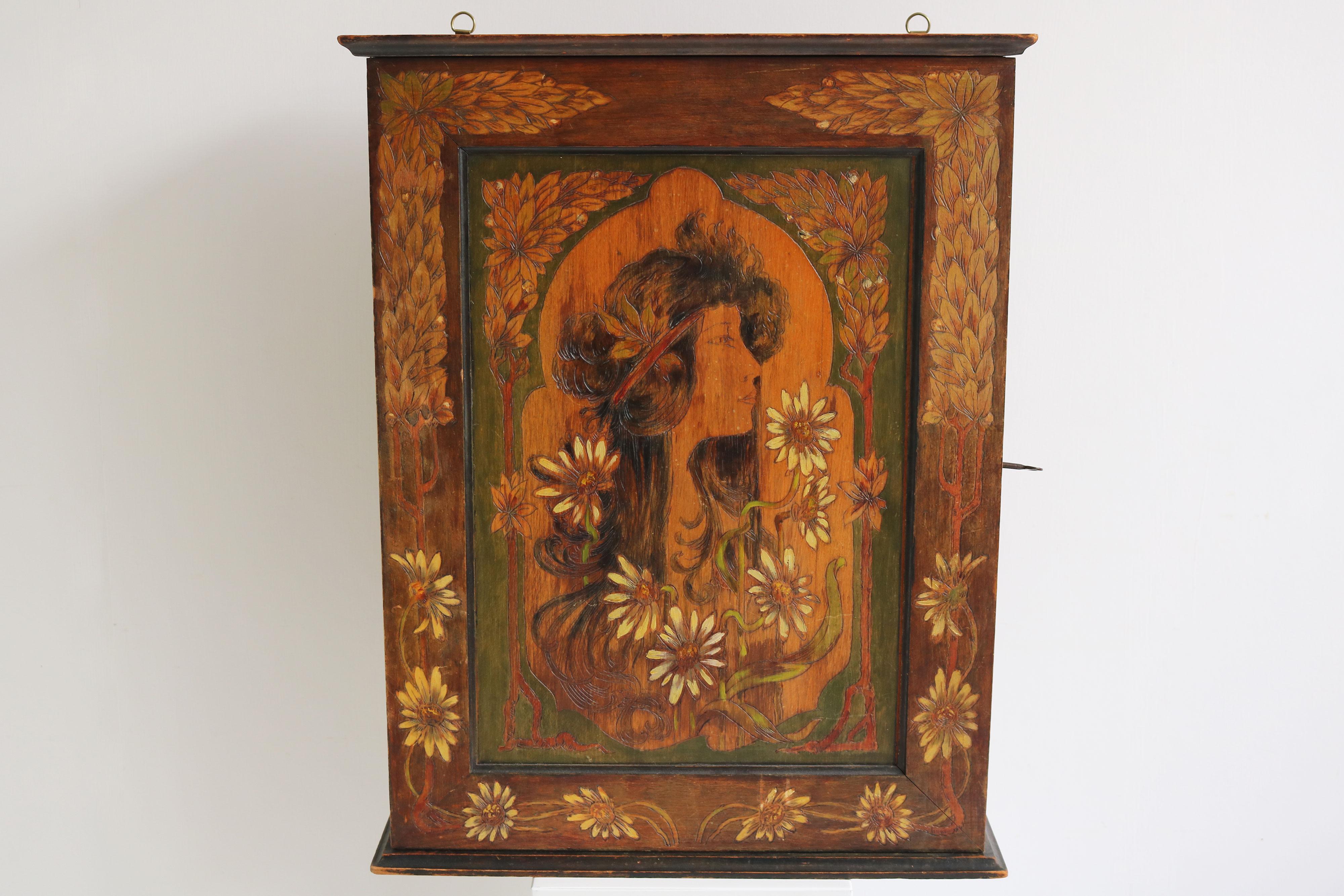 Precioso armario de pared/armario colgante Art Nouveau francés al estilo de Alphonse Mucha 1900. 
La pieza ha sido tallada y pintada a mano por los 3 lados mostrando una obra del estilo similar a la de Alphonse Mucha 
No está firmado, pero no hemos