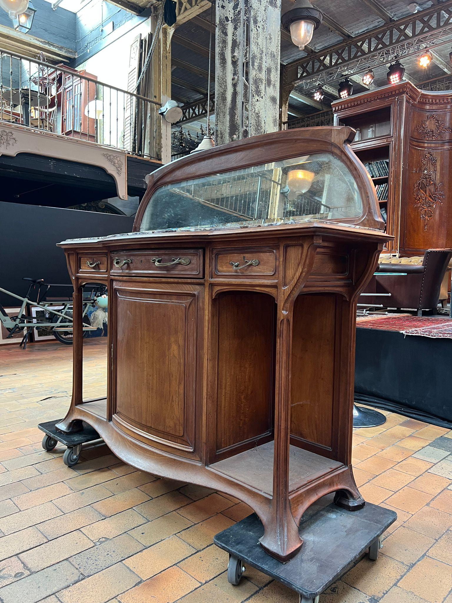 French Art Nouveau Molded Walnut Sideboard with Marble Top and Curved Mirror
France, Circa 1900

Elegant Art Nouveau sideboard crafted in molded walnut. The piece opens with three drawers and a central door, adorned with original brass handles. Its