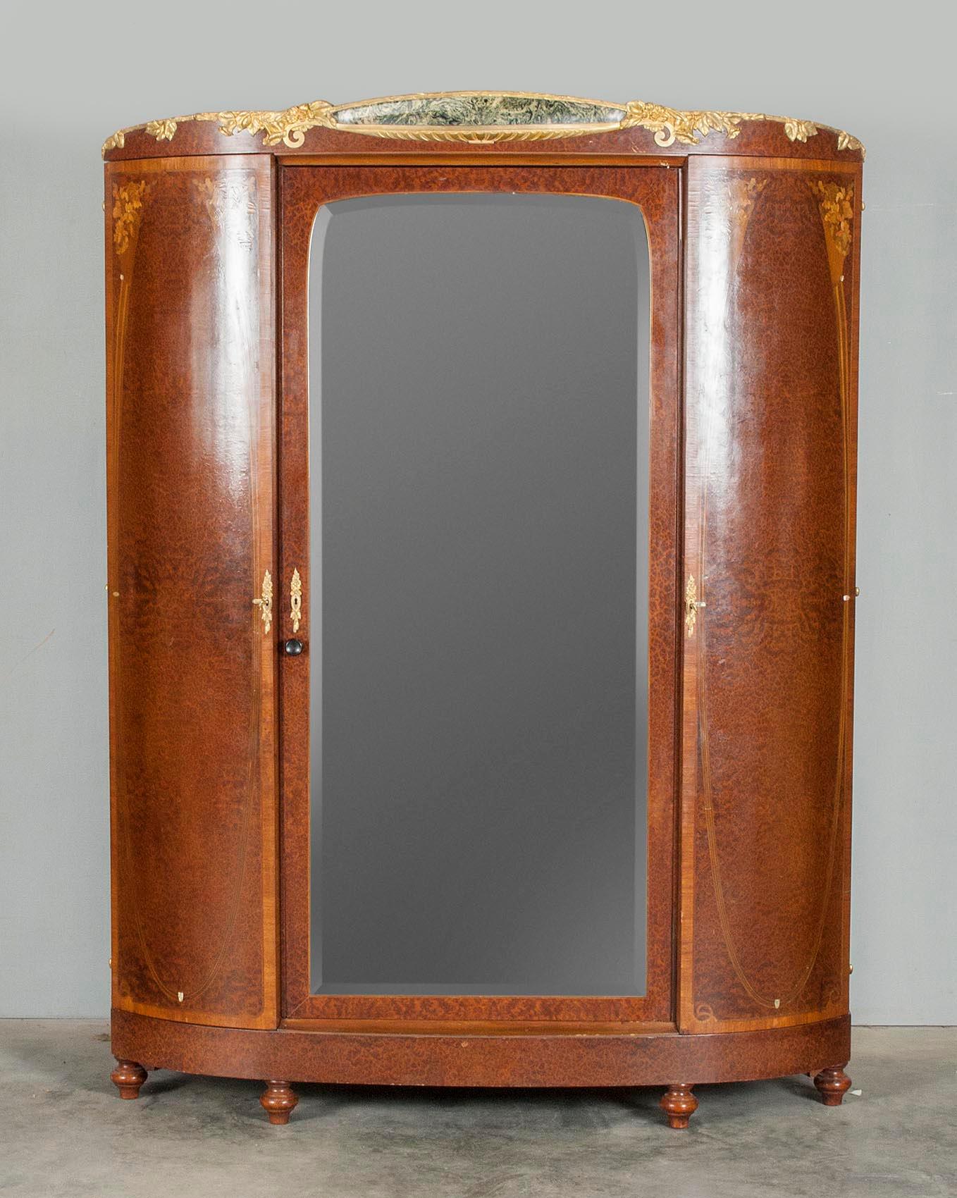 French wardrobe cabinet in Art Nouveau style.
This wardrobe cabinet has curved doors and a mirrored glass in the middle door.
The cabinet is veneered with mainly burr walnut and various other types of wood. Mother of pearl accents.
The base,