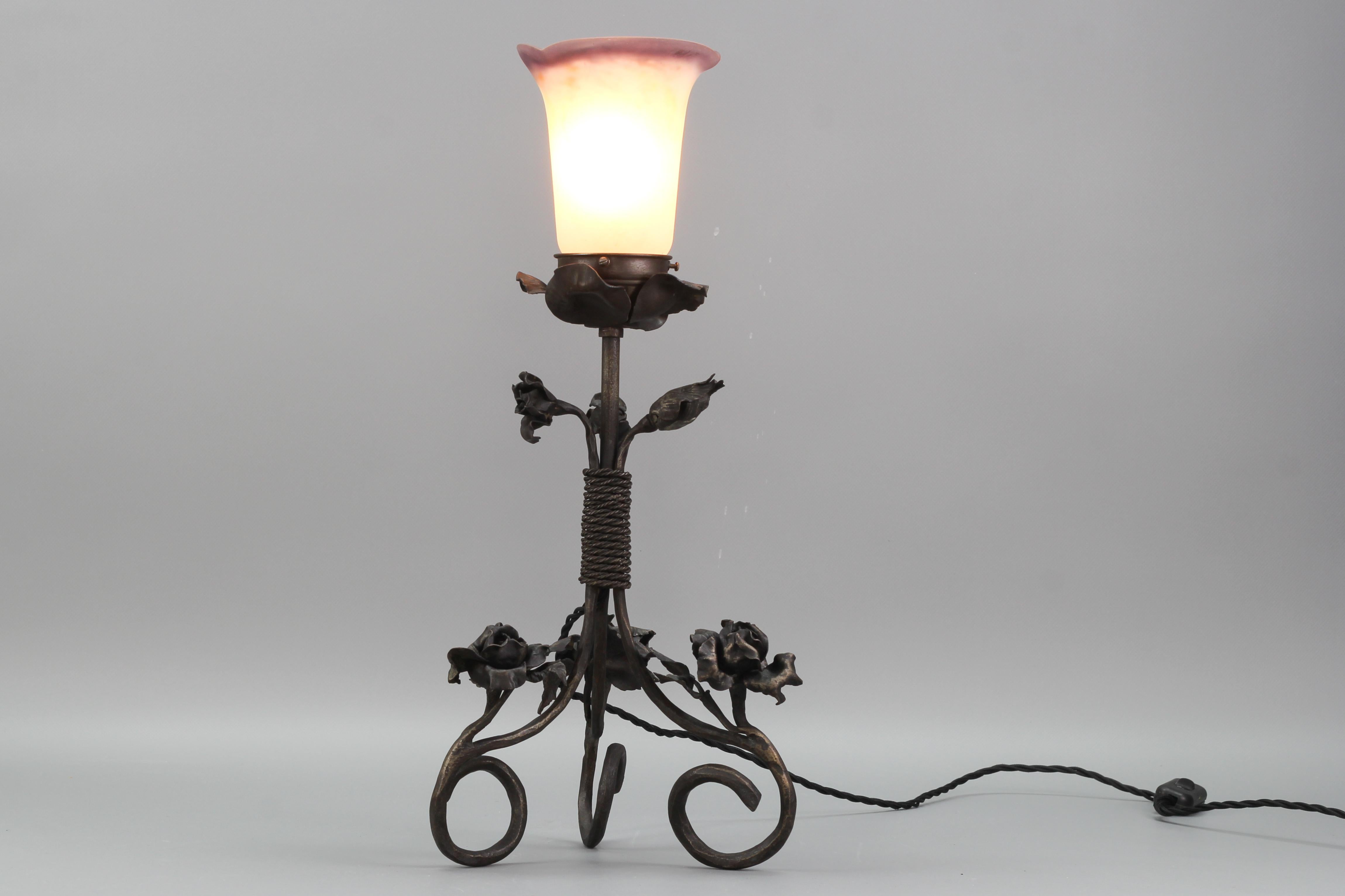 French Art Nouveau Wrought Iron and Pâte de Verre glass table lamp with Roses, circa the 1930s.
An adorable Art Nouveau style wrought iron table lamp with Pâte de Verre glass white and dark purple lamp shade. The wrought iron base features three
