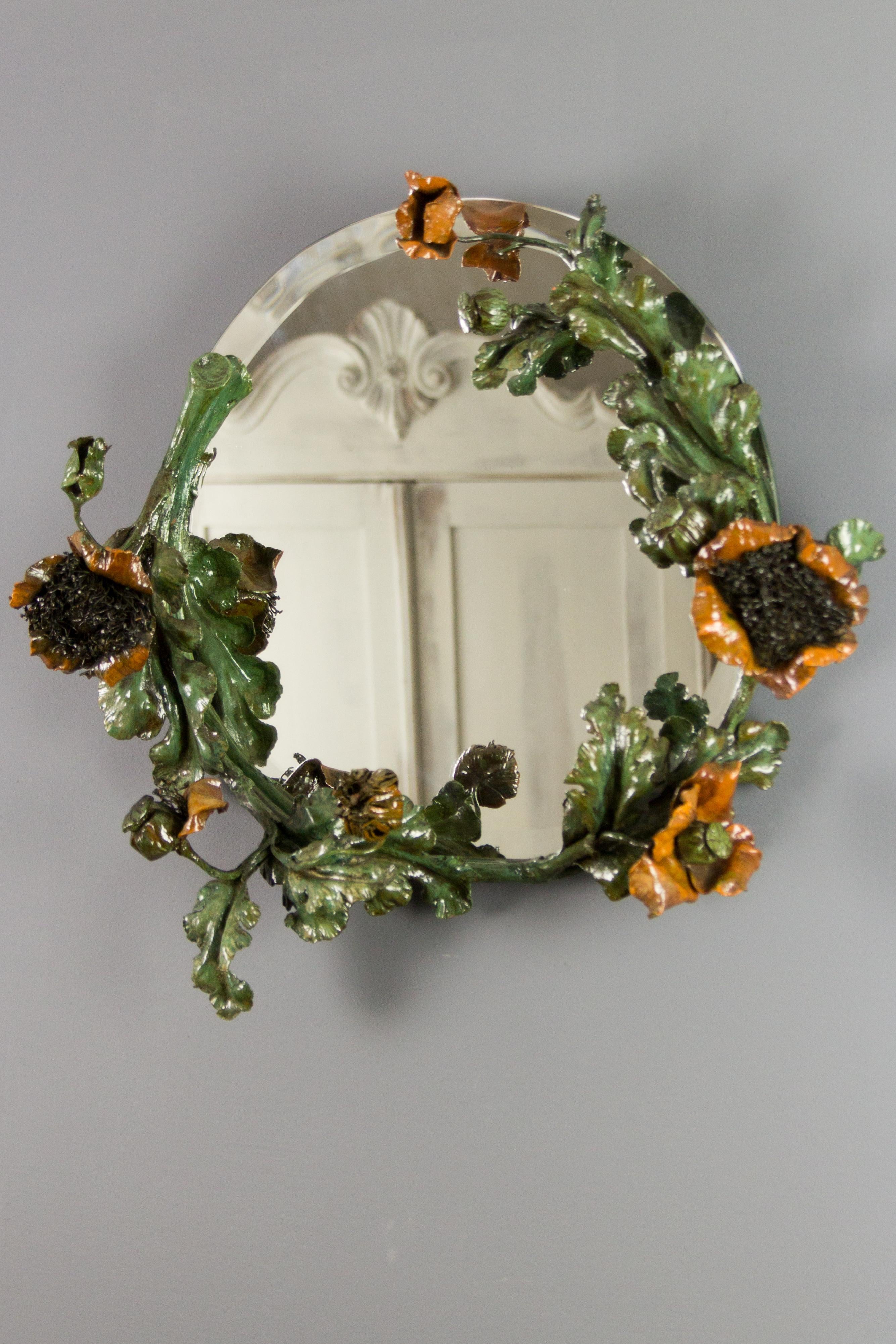 Impressive French Art Nouveau round wall mirror, frame made of wrought iron, features flowers, buds, fruits, and leaves of poppies, painted in green and dark orange color. Beautiful, natural, and realistic shapes. Round, beveled mirror,
