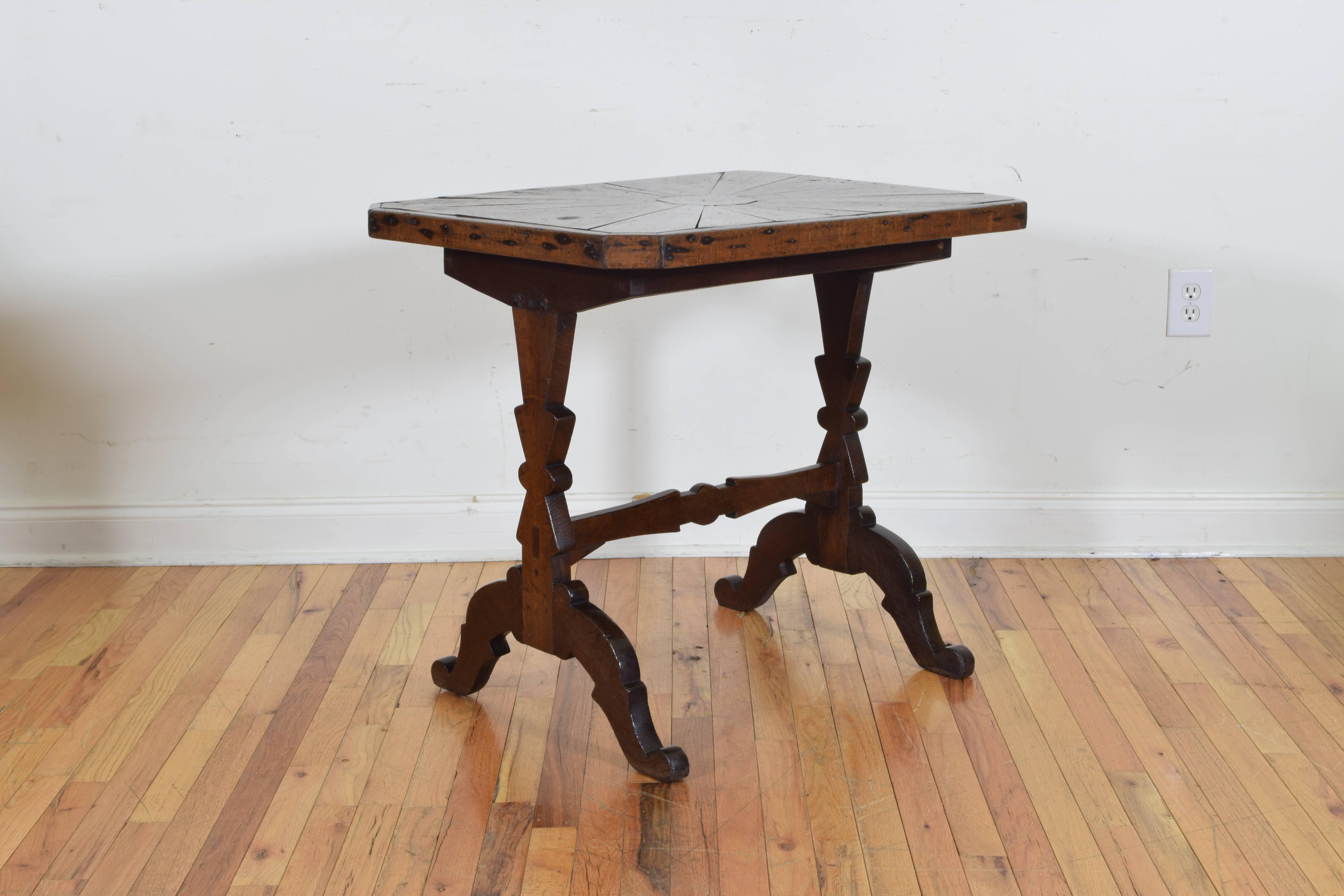 Having a rectangular top with canted corners, the veneers covering it radiating from a central sphere, raised on shaped trestle form legs connected by a shaped stretcher, a wonderful example of 