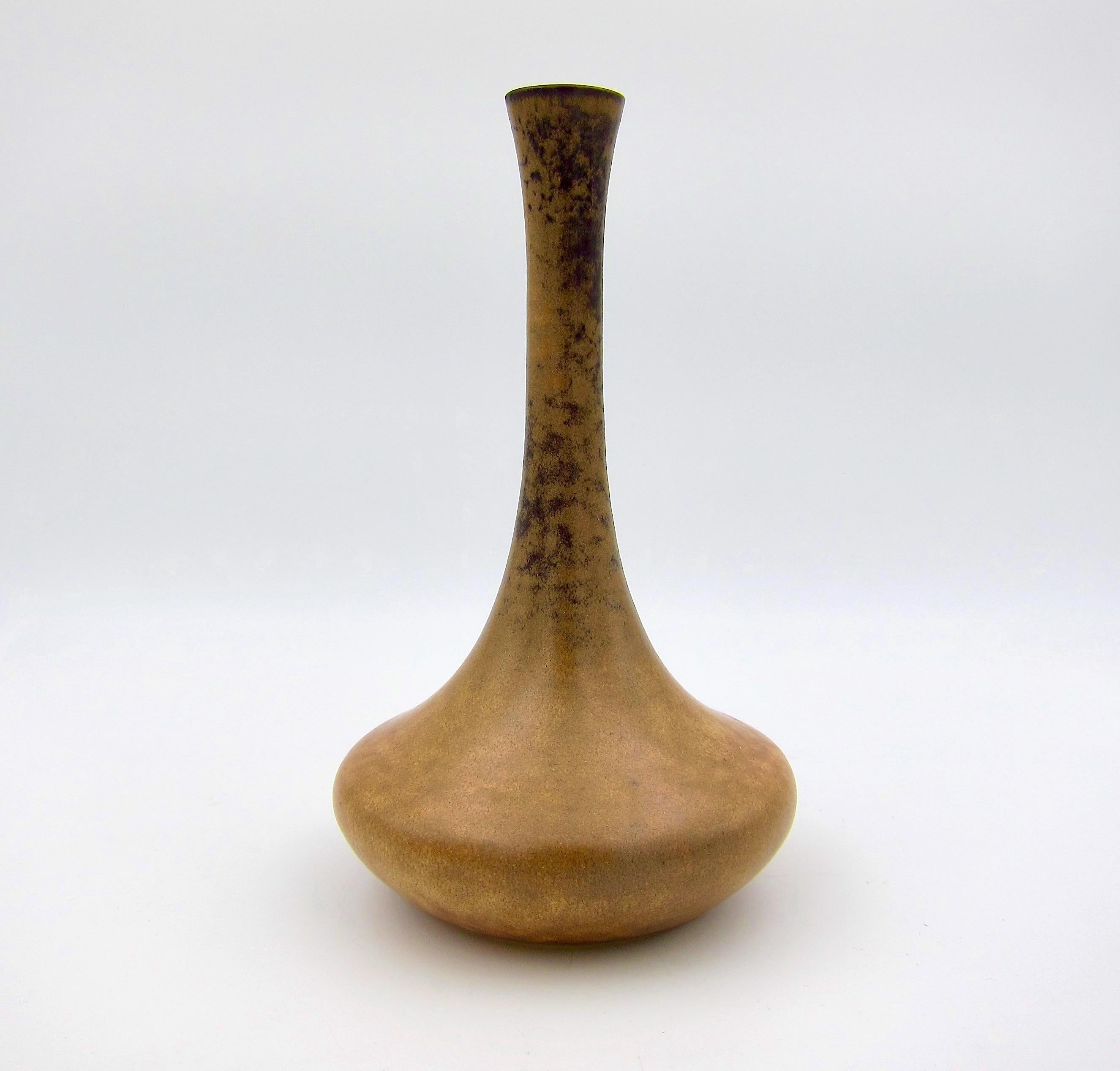 A handcrafted art pottery vase by Gabriel Musarra of Vallauris, France dating circa 1960s-1970s. The elegant bud vase features a swelling base and attenuated neck enveloped in a mottled brown matte glaze with dark brown (almost black) specked
