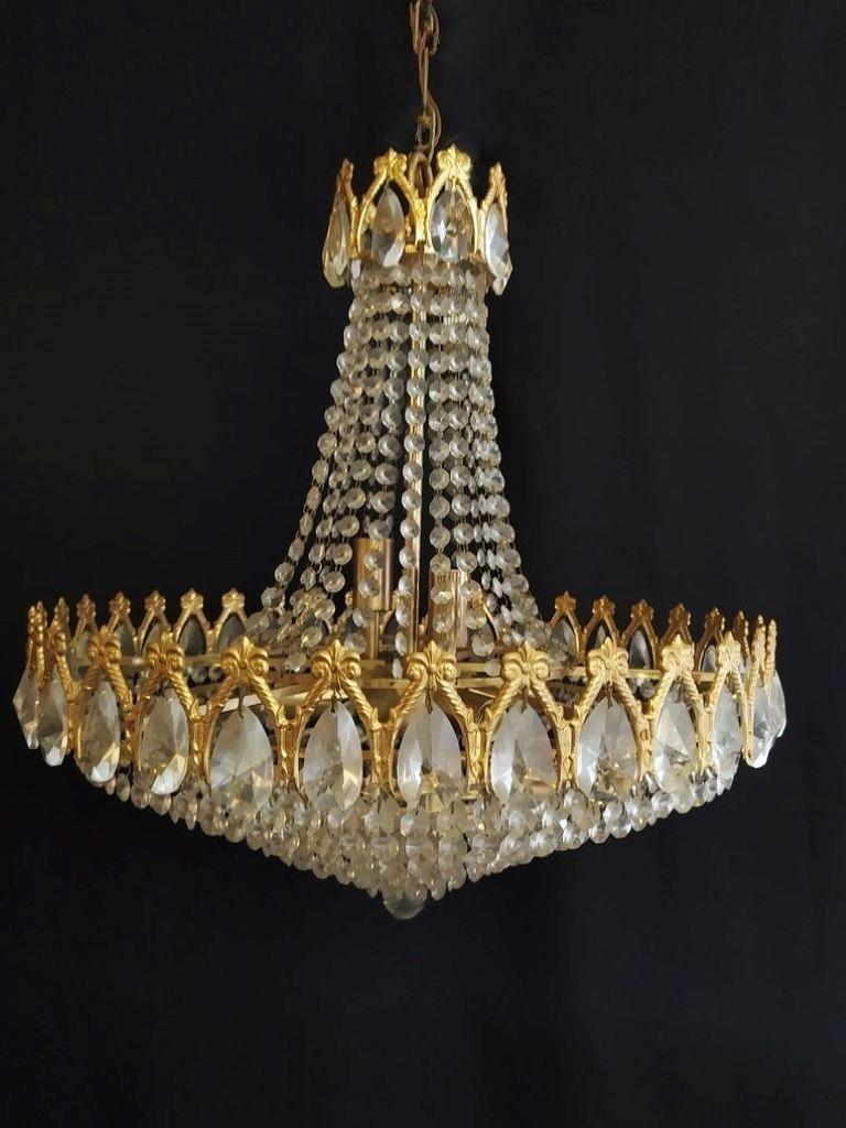 A very elegante Art Deco Period crystal eight-light chandelier, bronze frames in crown shape surrounded by large crystal prisms, France, 1930s. The chandelier is in very good vintage condition, beautiful aged patina to bronze, crystals complete and