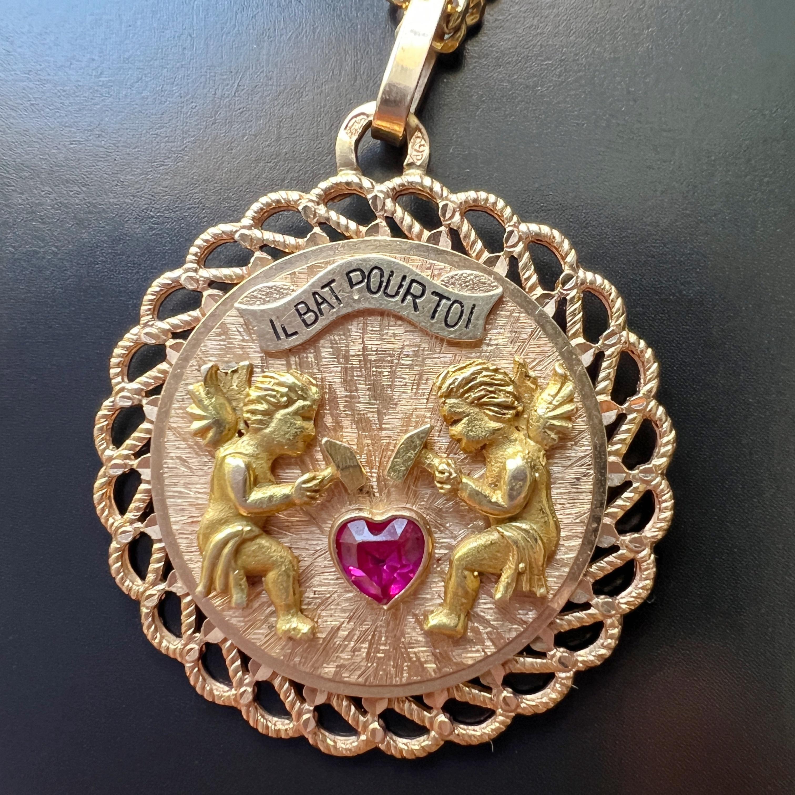 For sale a rare large vintage 18K gold pendant, expressing love and devotion captured in a circle shaped medal. The pendant is a French work and it features two winged angels, each delicately wielding a hammer, symbolizing the gentle beating of a
