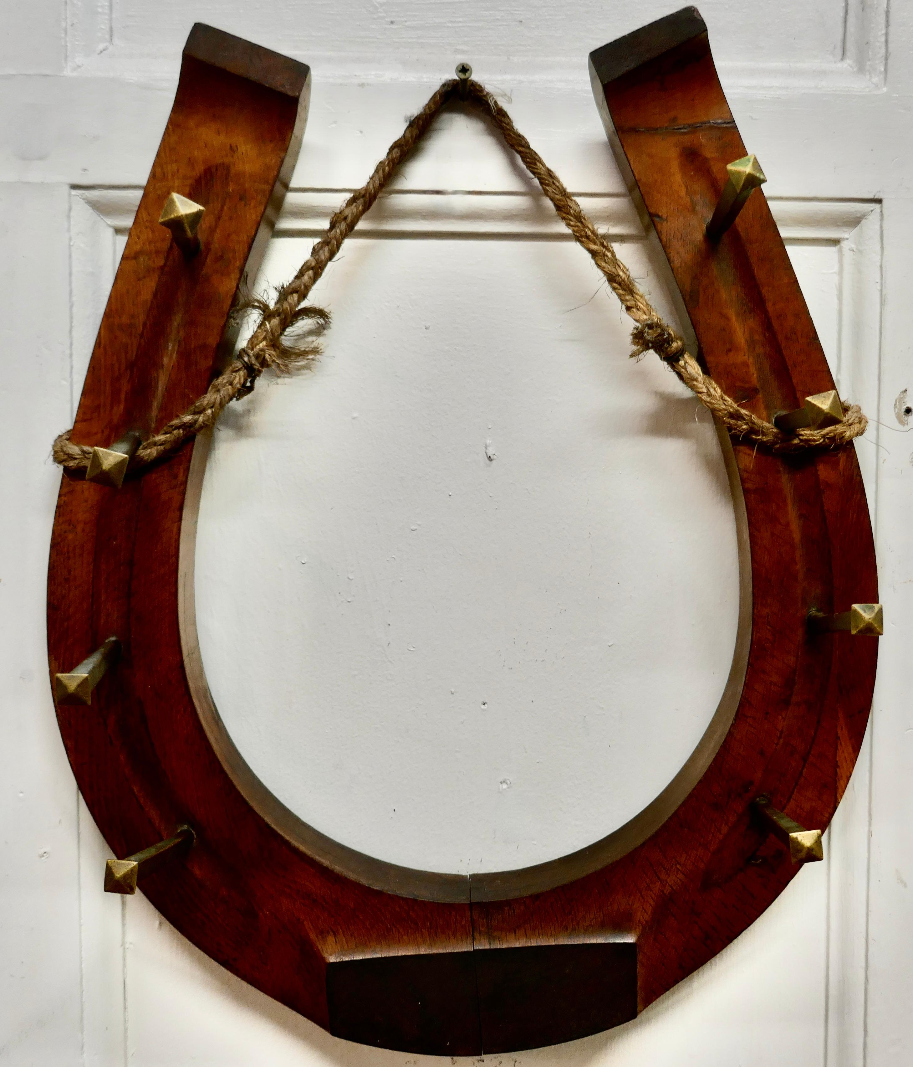 French Artisan folk art oak horseshoe coat hooks.

Beautifully made in 3” wide solid oak and in the shape of a horseshoe with 8 hand forged brass nails forming the hooks, good for coats or hats.
The rack is 18” high 15” wide and it is 4” out from
