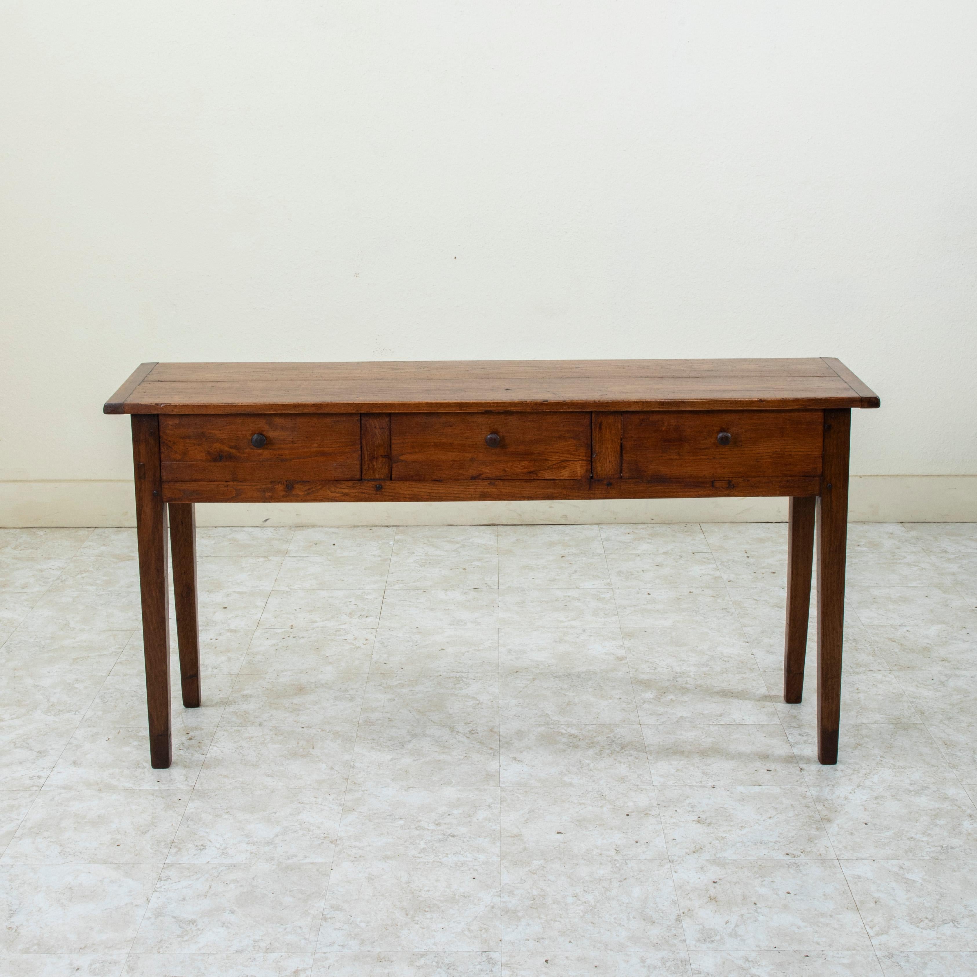 Provenant de la région de Normandie, en France, cette console ou table de canapé en chêne fabriquée artisanalement au tournant du XXe siècle est construite à la main et repose sur des pieds carrés effilés. Trois tiroirs équipés de poignées à bouton,
