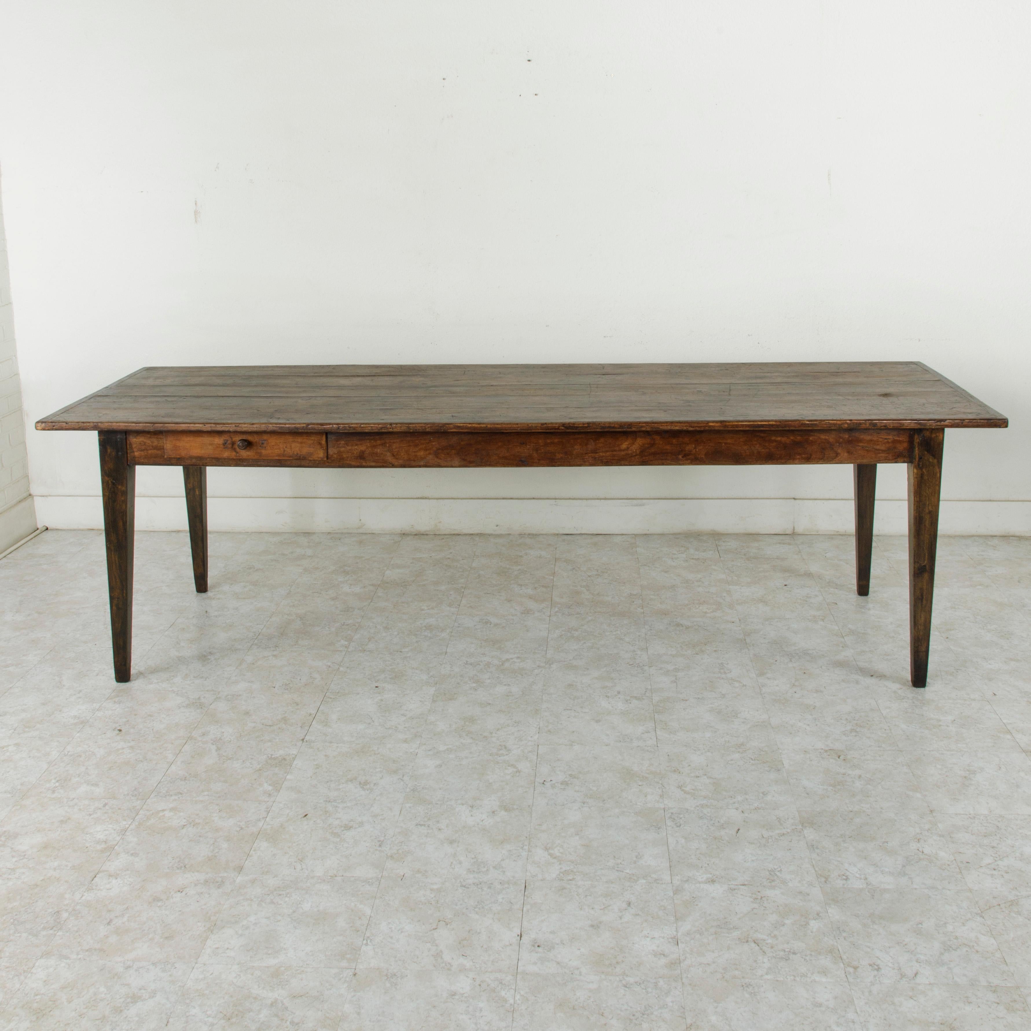 This turn of the 20th century artisan-made farm table is from the region of Le Perche, a Sub-region of Normandy, France. Its oak top is constructed of five planks of wood and measures 103 inches long and 36 inches wide. A pull out / pull-out cutting