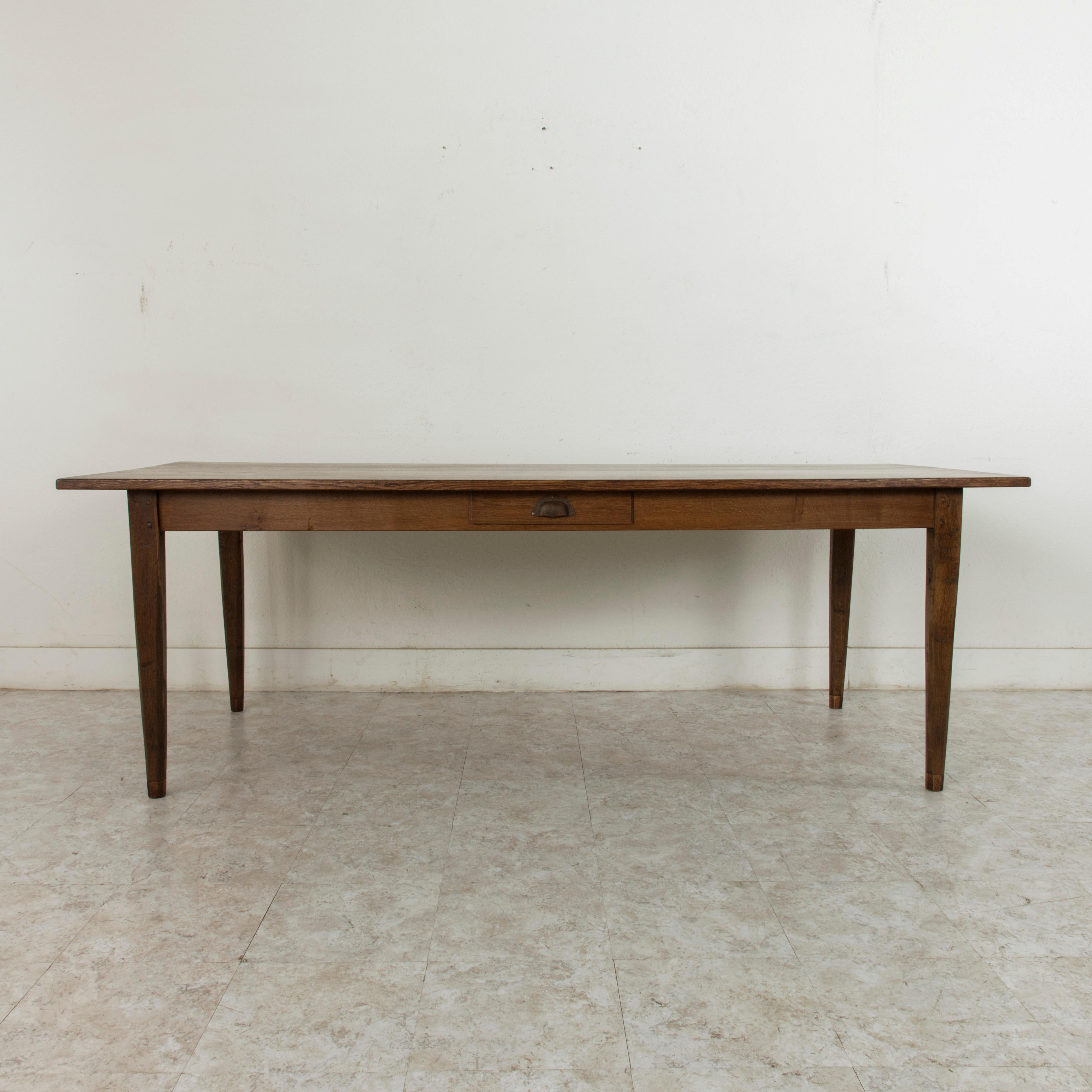 This turn of the 20th century artisan-made farm table is from the region of Le Perche, a sub-region of Normandy, France. Its oak top is constructed using mortise and Tenon joinery and measure 86 inches long and 36.5 inches wide. Resting on a hand