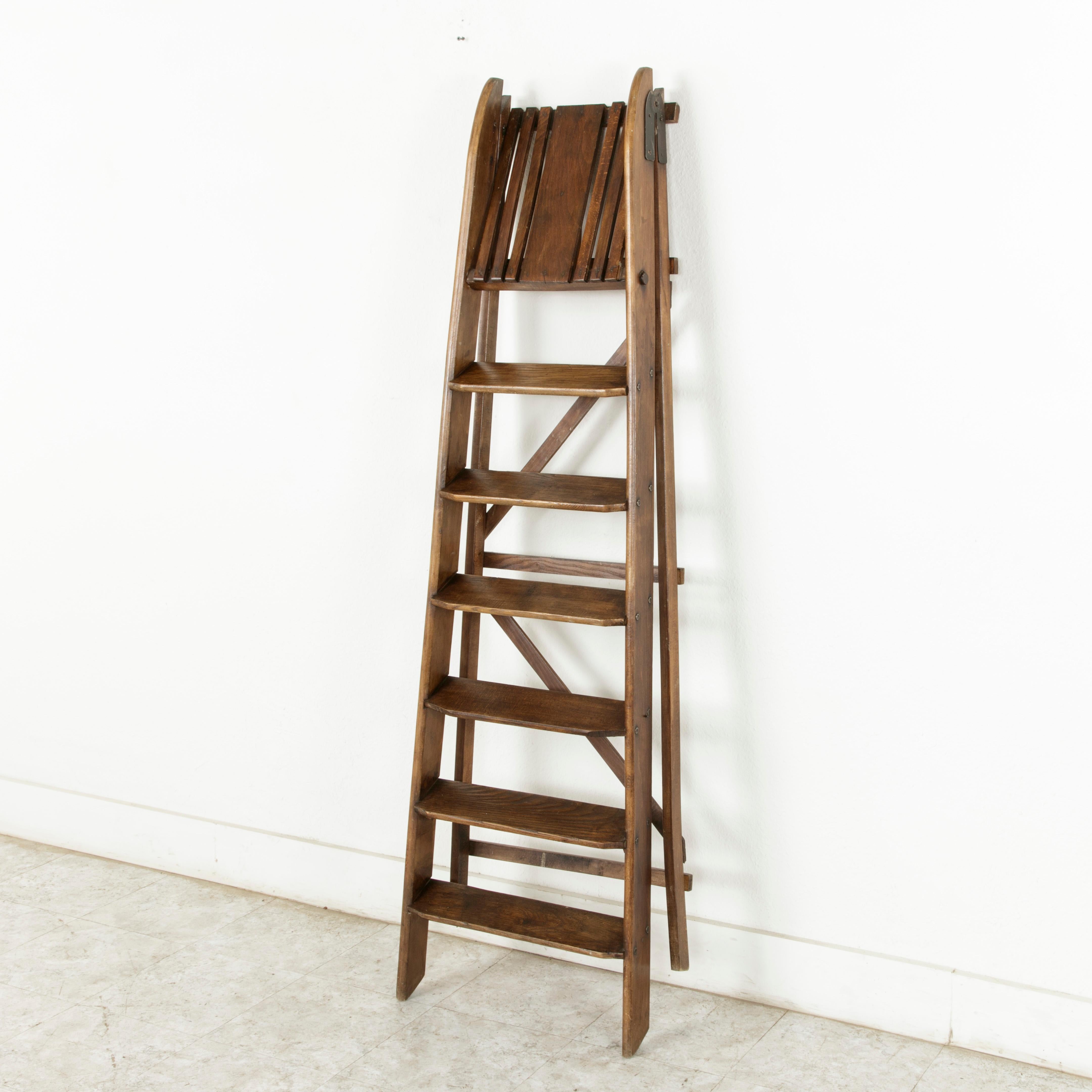 This artisan-made French library ladder from the turn of the 20th century features iron hinges that allow it to be folded flat for storing. Constructed using mixed woods, a practice common among artisans of the period, this ladder is fitted with six