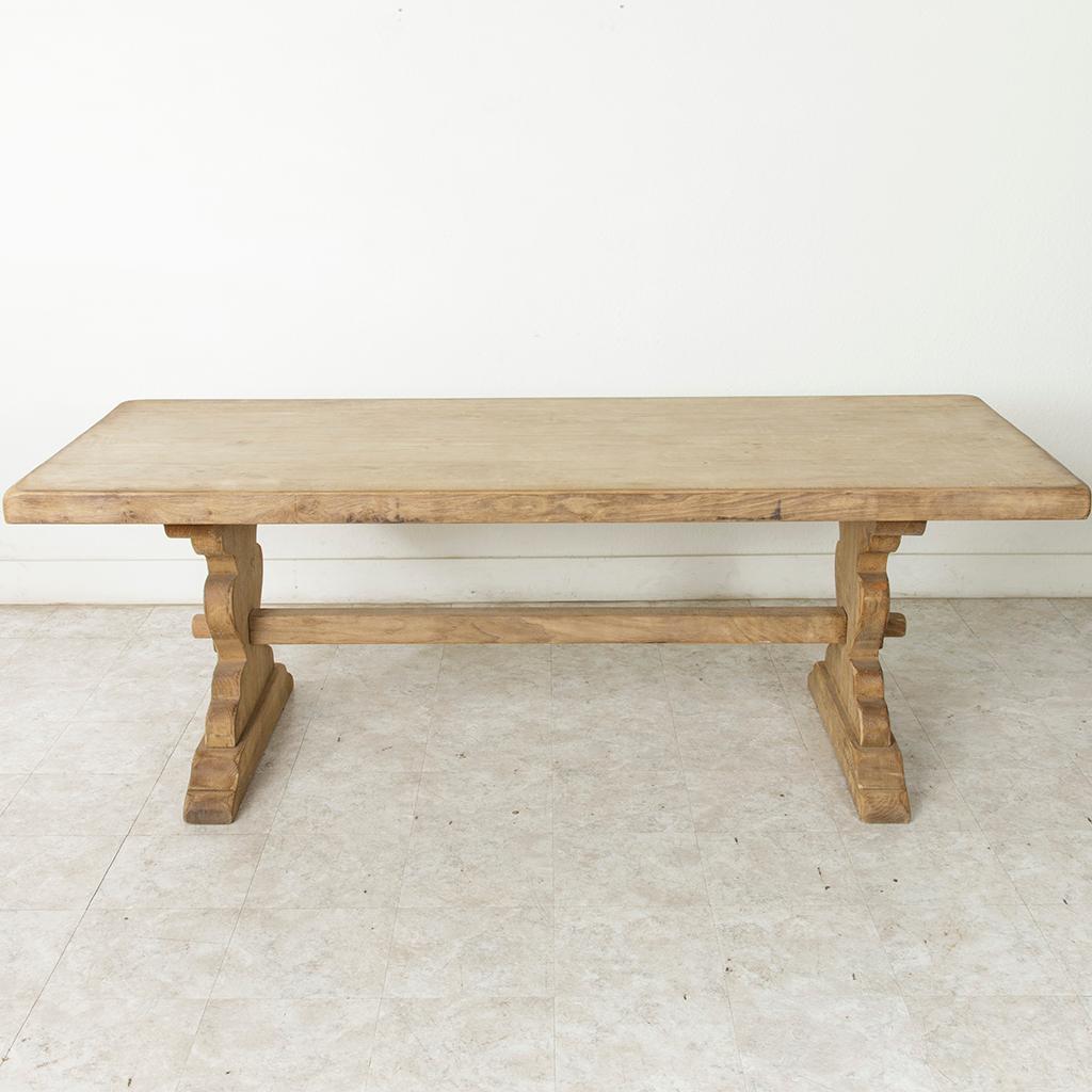 From the region of Normandy, France, this artisan-made oak monastery table or dining table from the turn of the 20th century features a three-inch thick top constructed of seven planks of wood. Resting on a sturdy trestle base constructed using